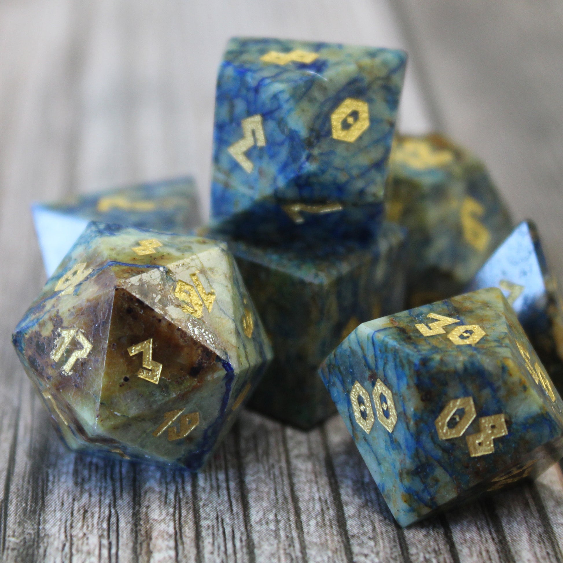 Close-up of Azurite dice set on a wooden surface, showcasing the veins of blue and green, and the gold numbering.