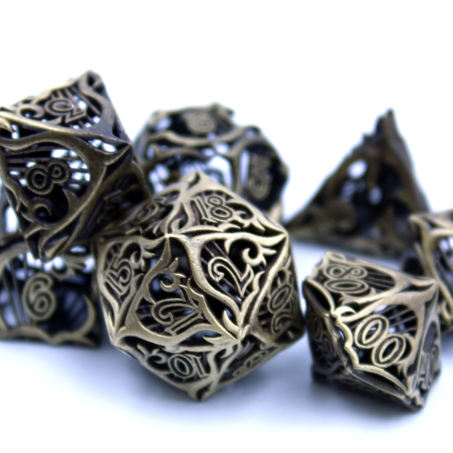 Closeup of a set of seven bronze bard-inspired hollow metal RPG dice with uninked numbers on a white background