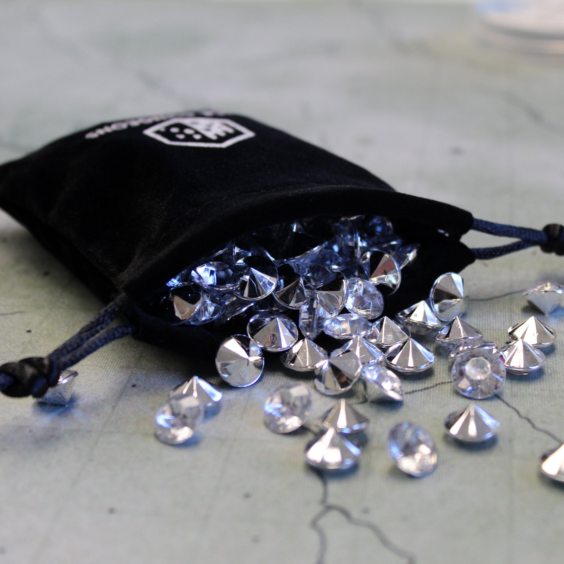 drawstring bag with dice dungeons logo spilling out rpg game tokens.