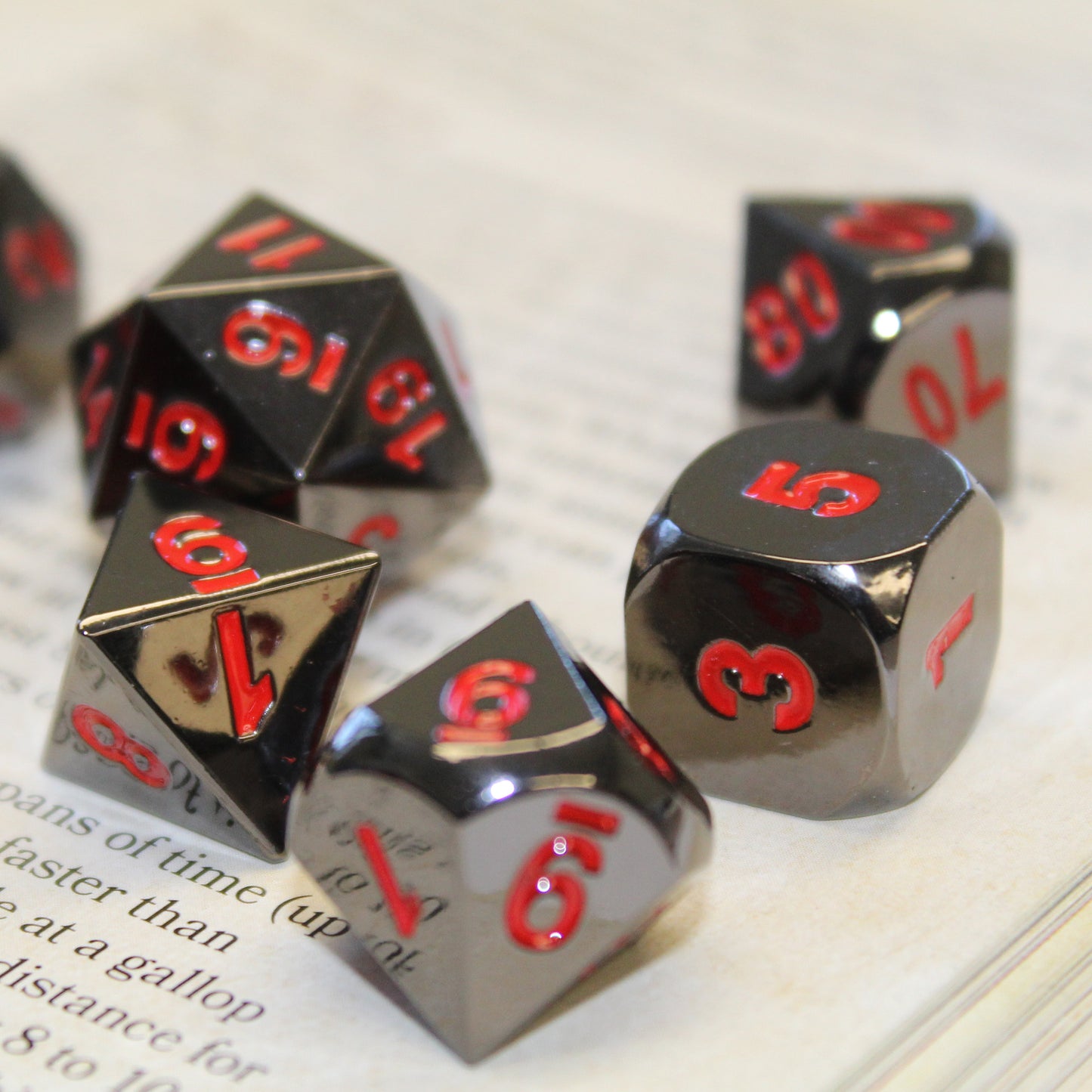 Five Metal Black Ember dice scattered on top of an open book