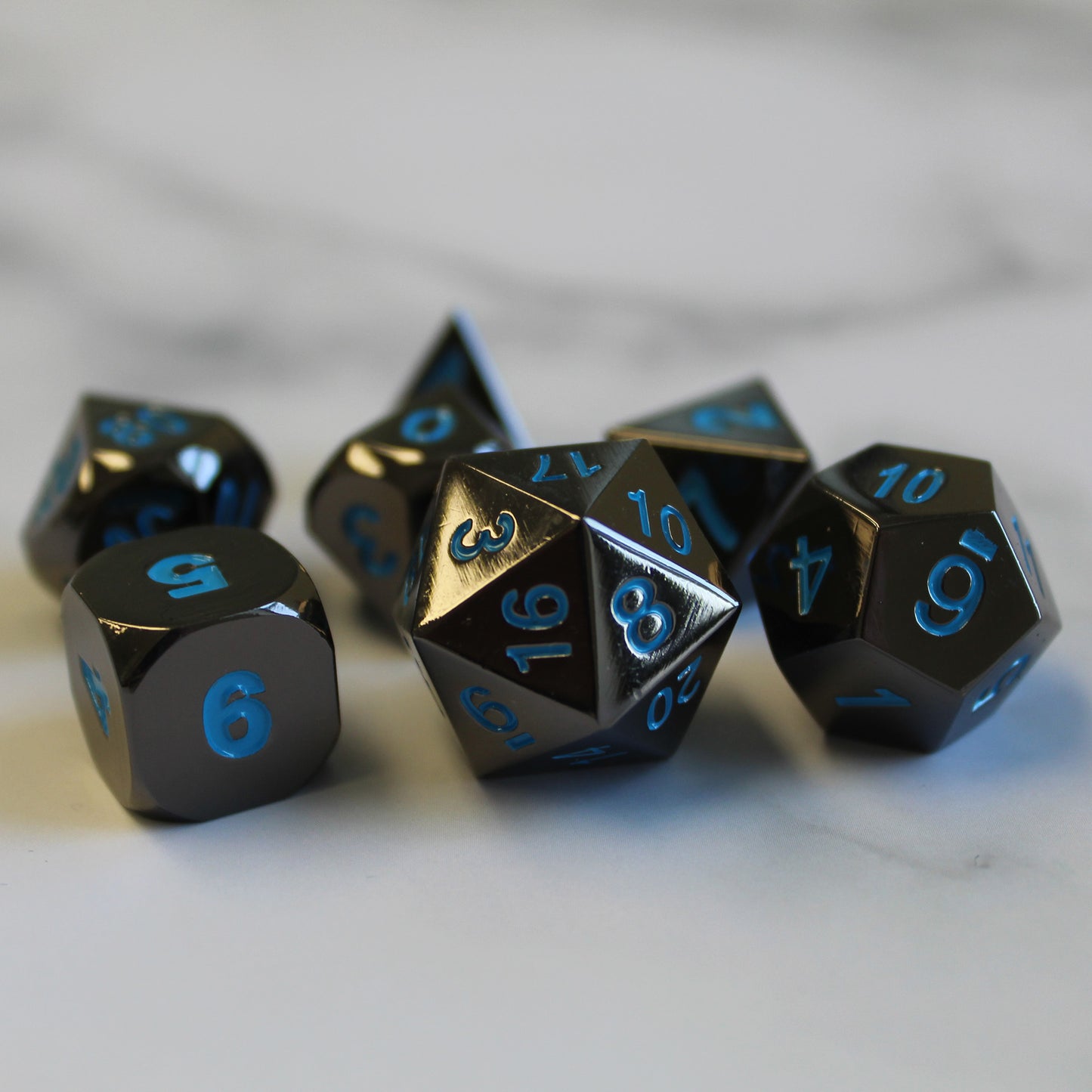 Metal Black Frost dice set arranged on top of a marble surface