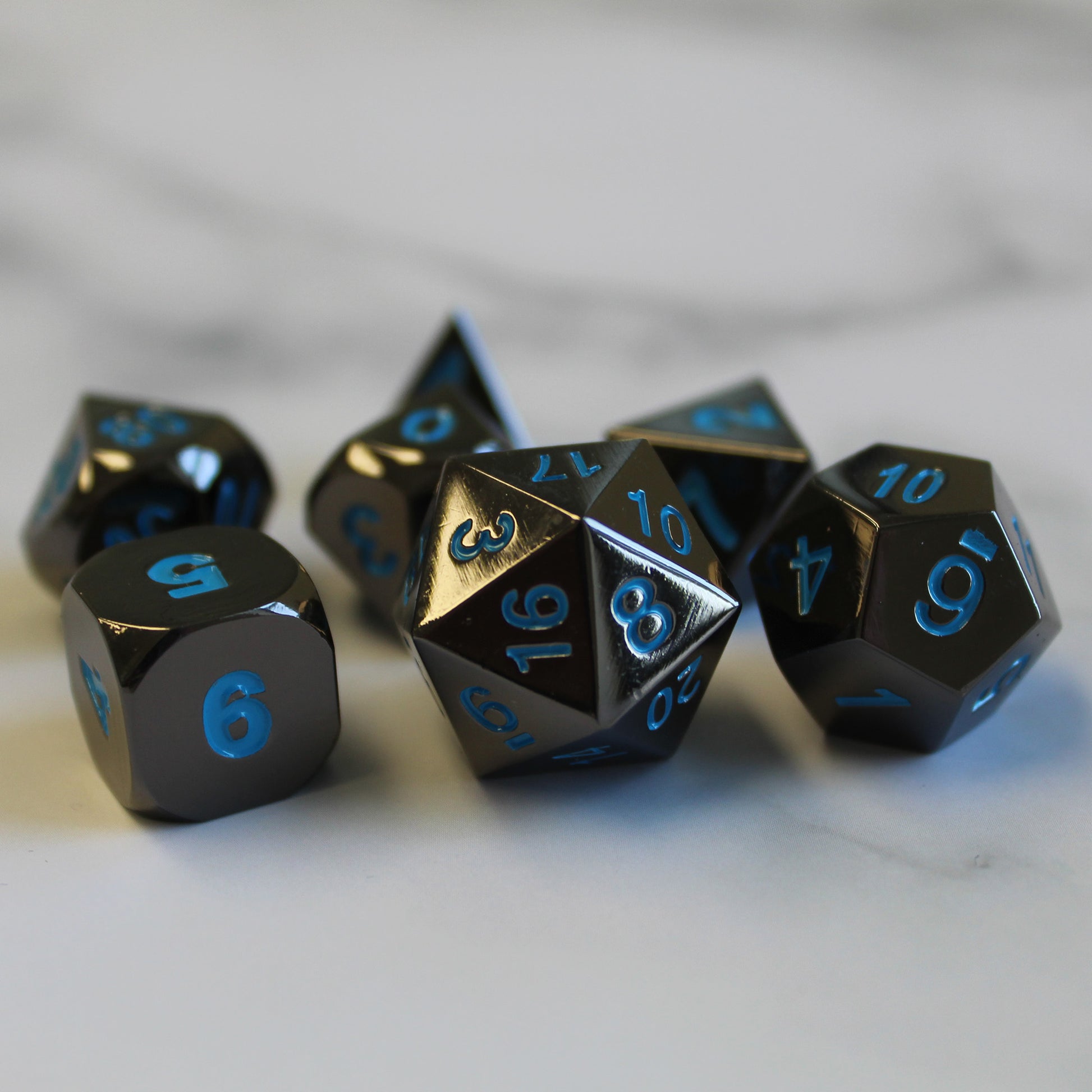 Metal Black Frost dice set arranged on top of a marble surface