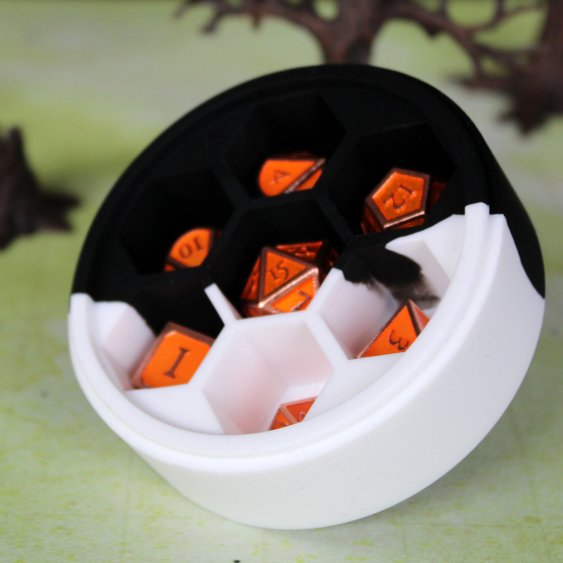 Silicone Round Dice Case on a D&D table, holding an orange metal dice set (not included.