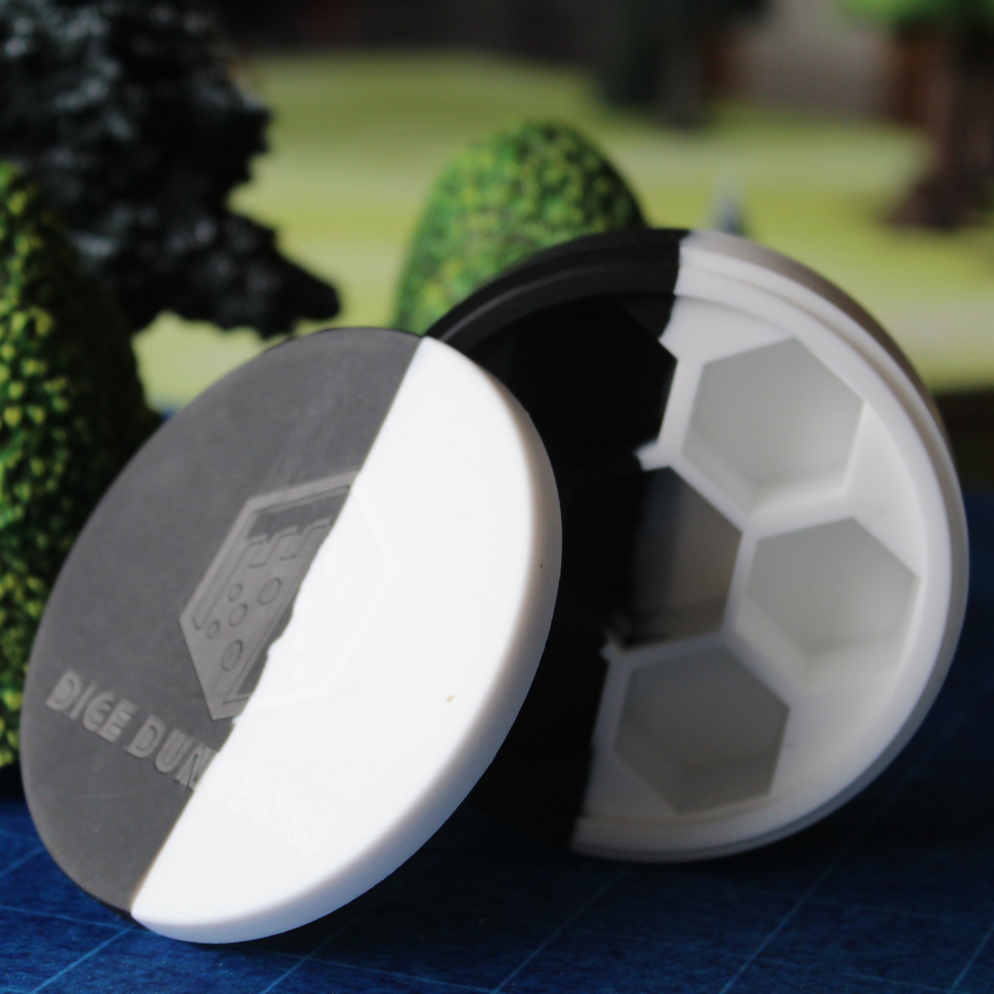 Silicone Round Dice Case standing upright on a table, with the Dice Dungeons logo stamped on the front of the lid.
