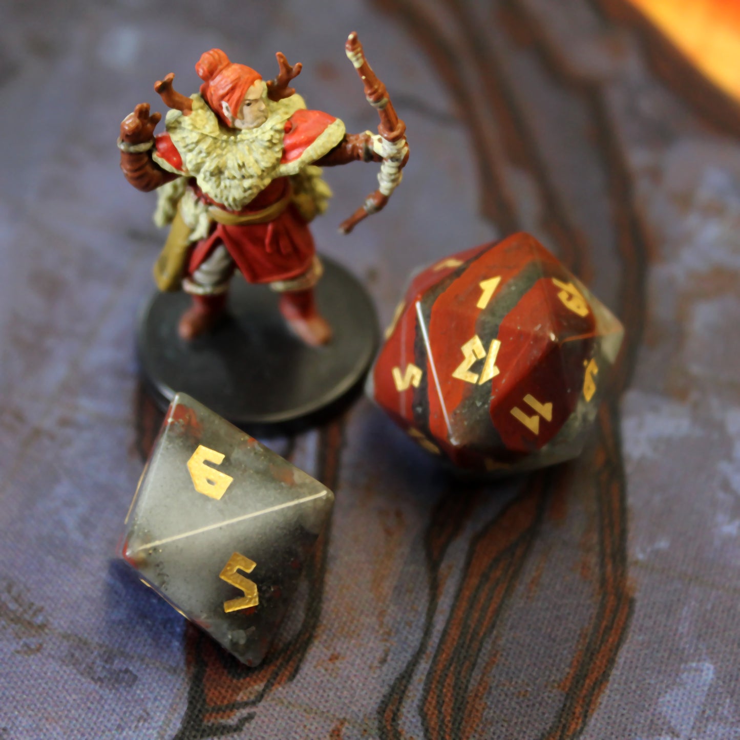 Close-up of the full Bloodstone dice set, highlighting vibrant red hematite spots and intricate gold leaf numbering on the green chalcedony dice.