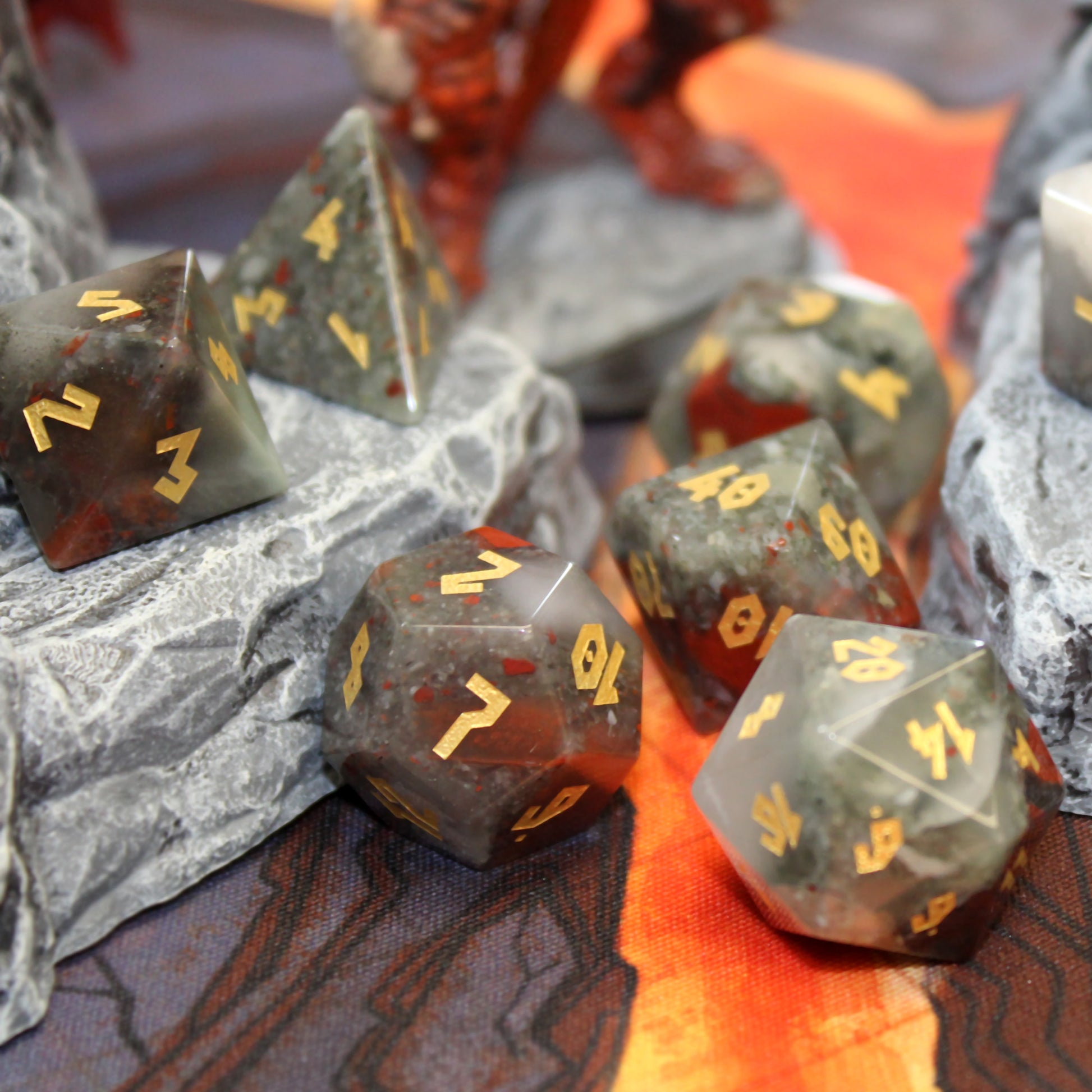 Close-up of the Bloodstone dice set, showcasing the unique color variations of the gemstone dice with gold leaf numbering on each die.