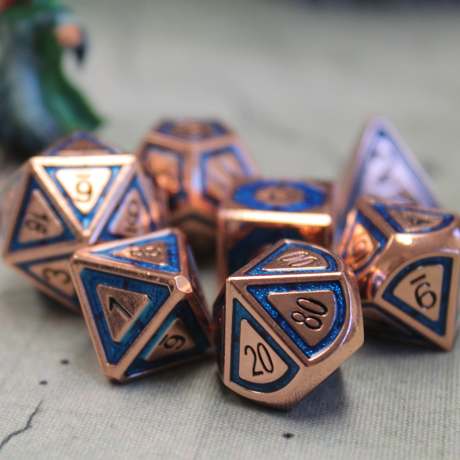 BullsEye Blue Dice on a cloth mat.  These dice feature a copper plated coloring on the raised surfaces and a semi-transparent UV hardened enamel inset ring with black numbering for high contrast legibility.