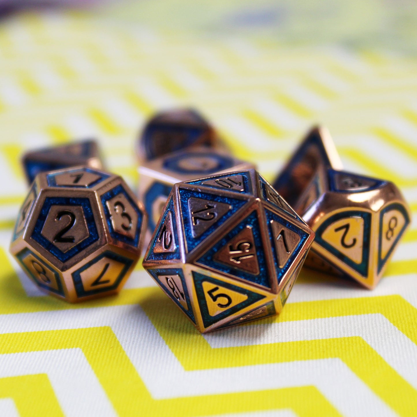 Close up shot of the BullsEye Blue RPG dice set with the d20 in the foreground on a yellow and white zigzag surface showcasing the simple numbering for easy reading.