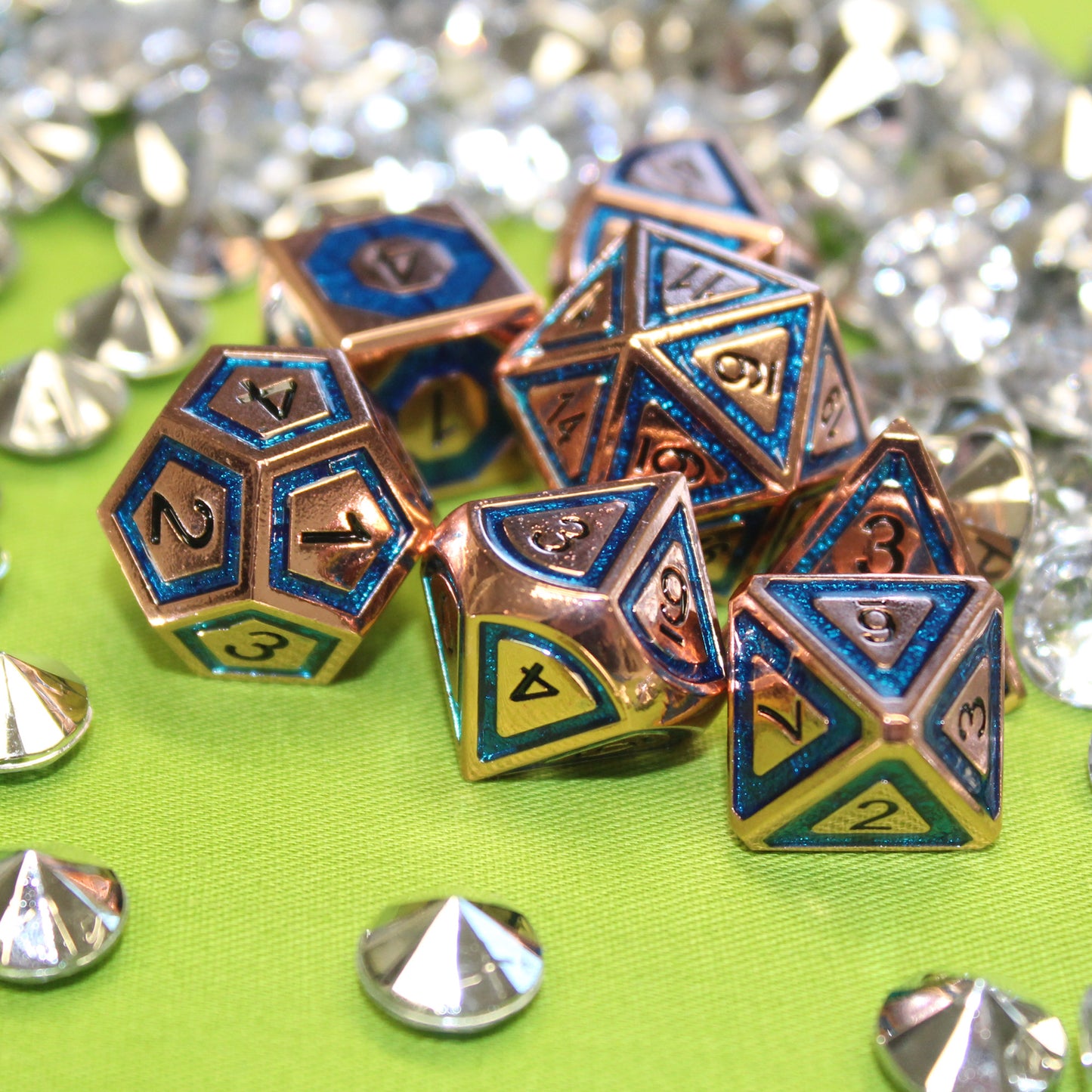 BullsEye Blue Dungeons & Dragons Dice set arranged scattered on a green cloth with decorative gems surrounding the set.  The d12, d10, and d8 dice are closest to the viewer.