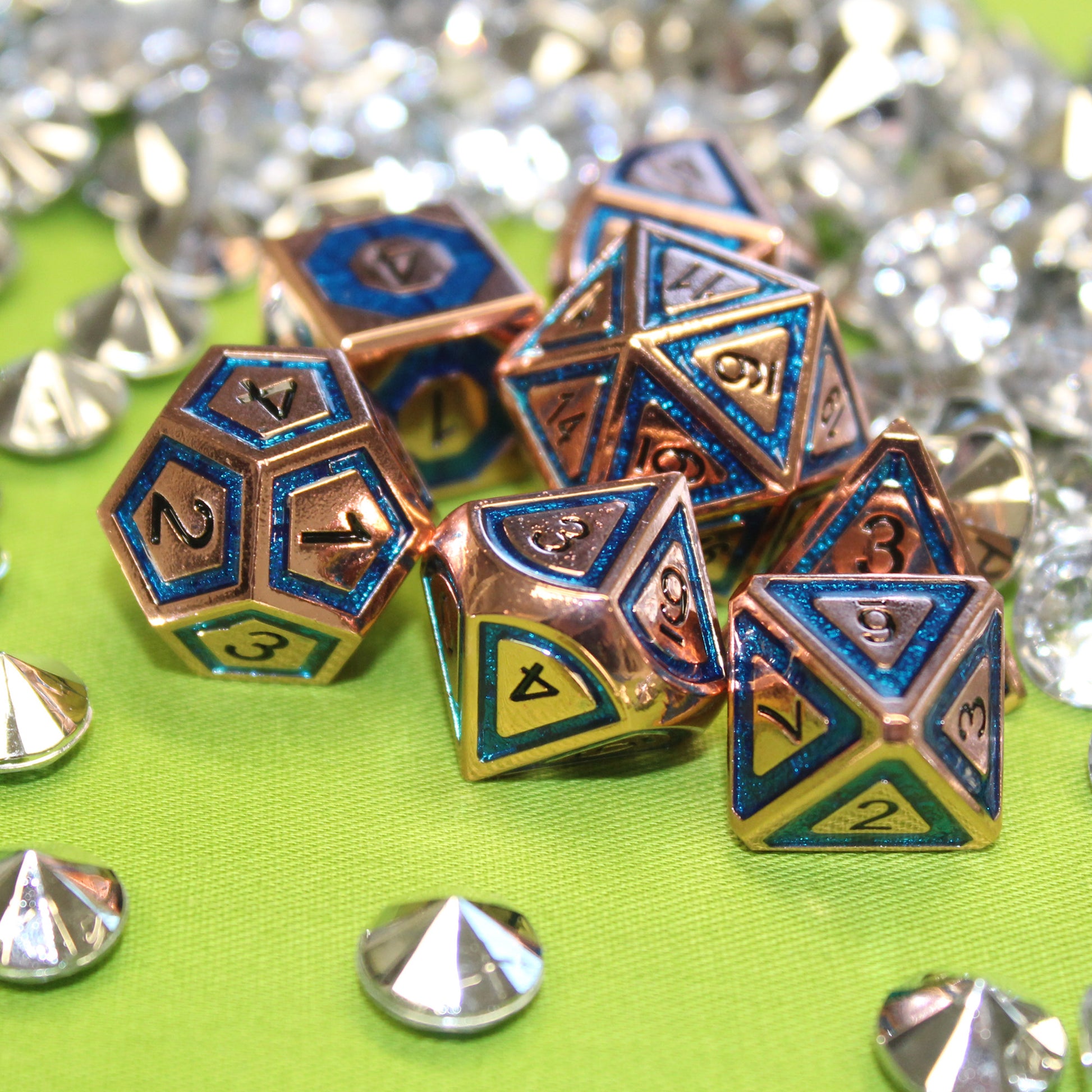 BullsEye Blue Dungeons & Dragons Dice set arranged scattered on a green cloth with decorative gems surrounding the set.  The d12, d10, and d8 dice are closest to the viewer.