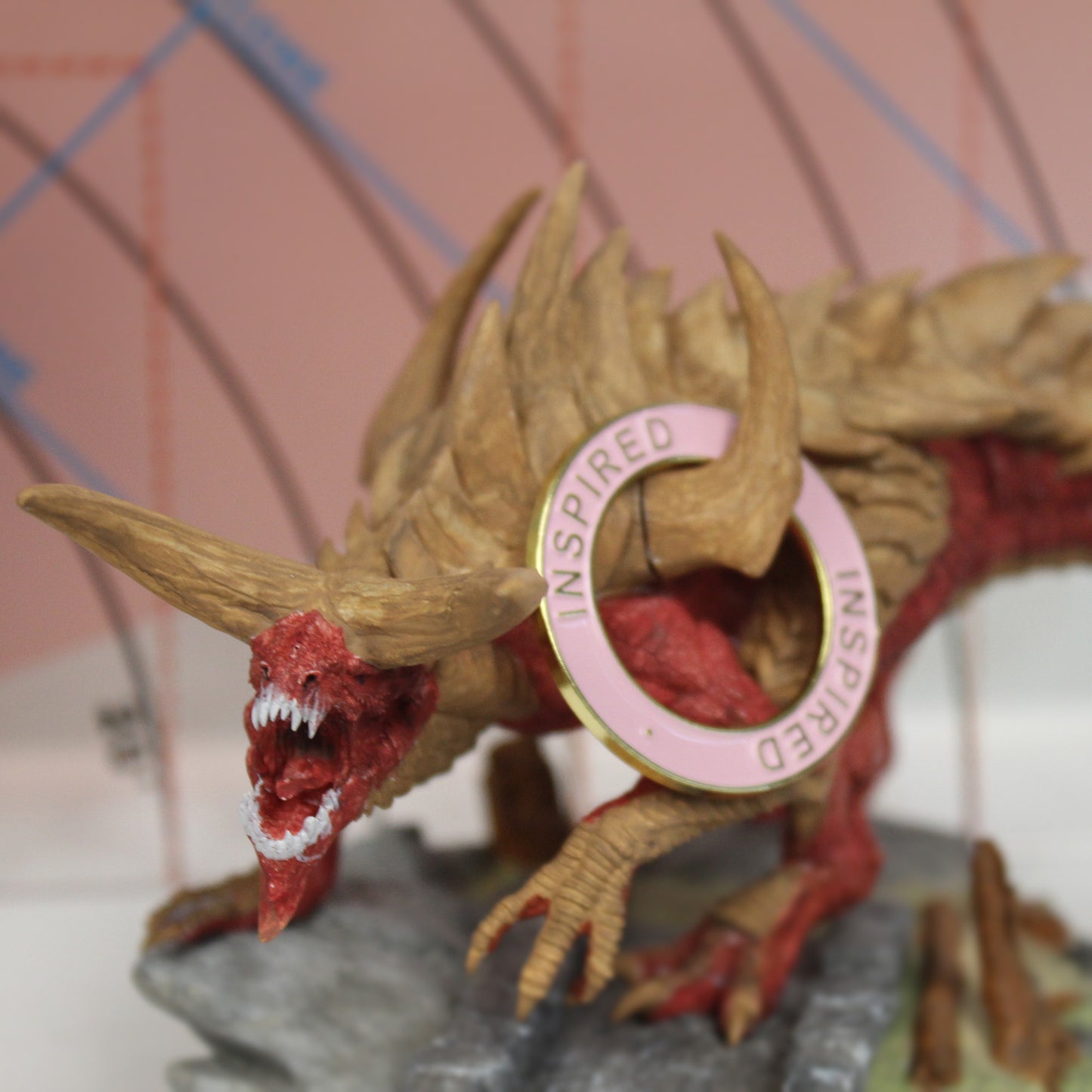 Gold metal Inspired condition ring with pink enamel hanging on a large monster miniature, perfect for tracking inspiration on oversized figures.