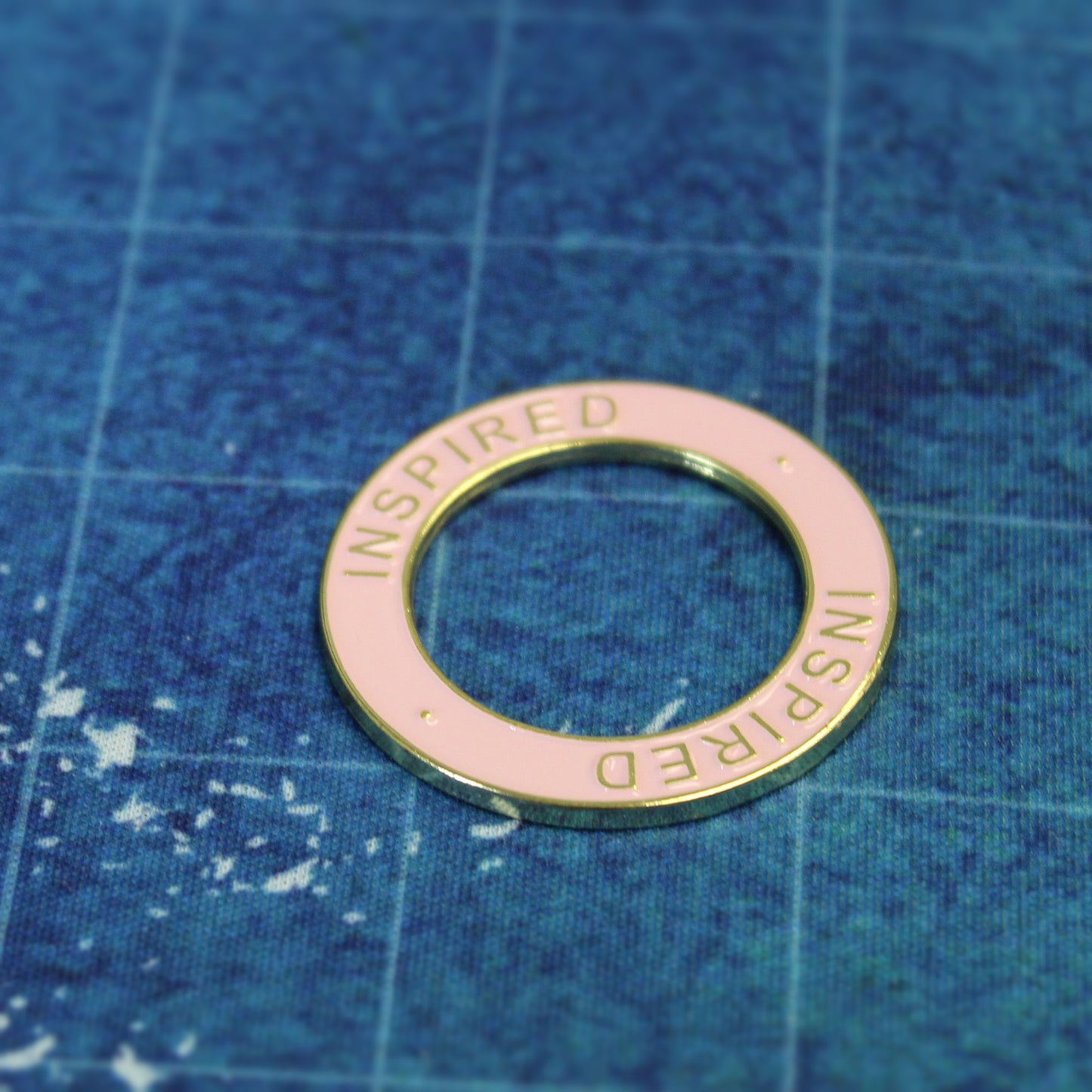 Inspired condition ring with gold metal and pink enamel, used on a miniature on an ocean-themed grid to track inspiration effects in a nautical RPG setting.