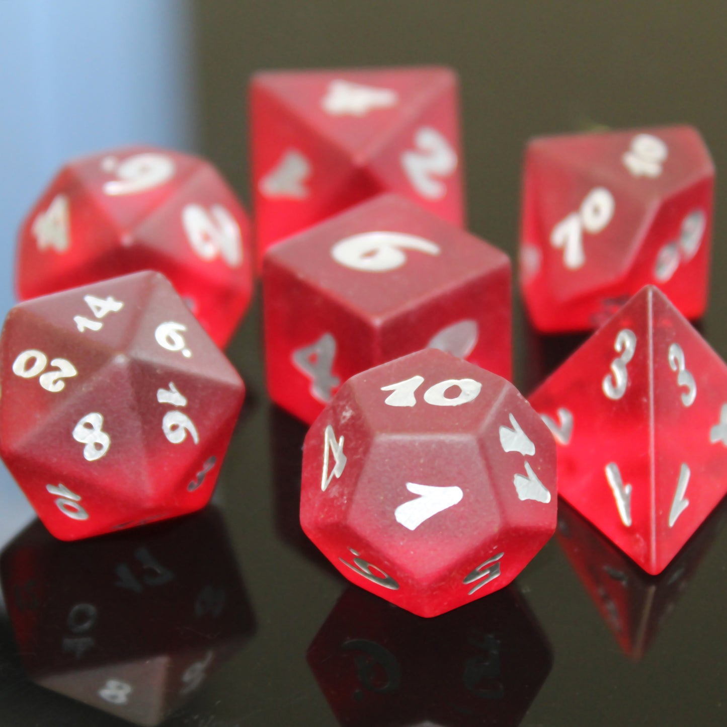 Closeup of a set of red translucent glass RPG dice with silver numbering