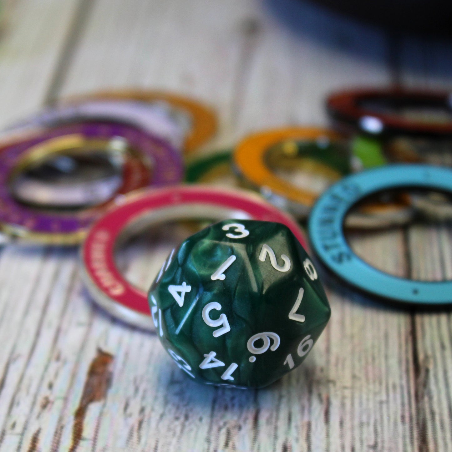 Green Pearl D30 dice on a gaming table next to condition rings, adding a unique element to the tabletop setup.