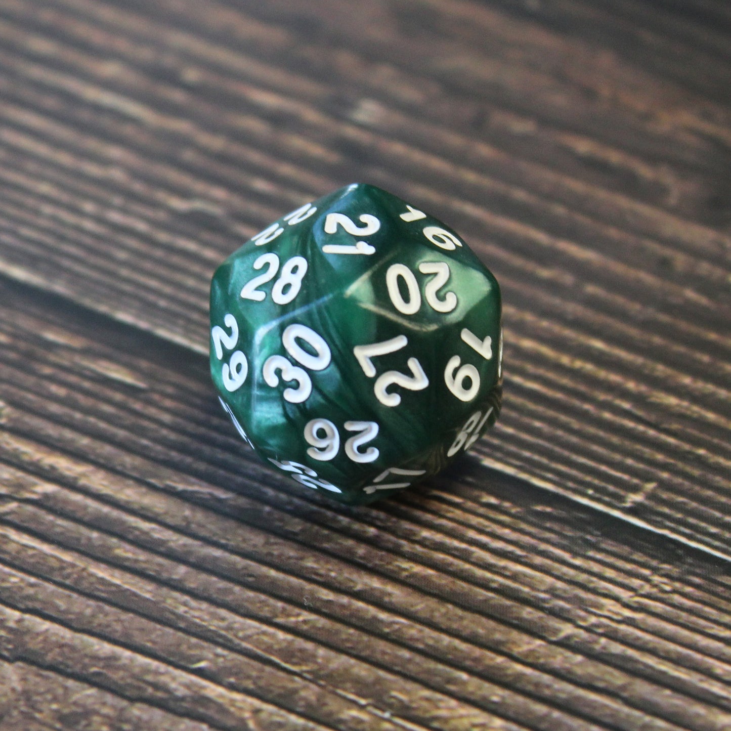 Green Pearl D30 dice displayed on a table, featuring a pearlescent hunter green color with white numbering.