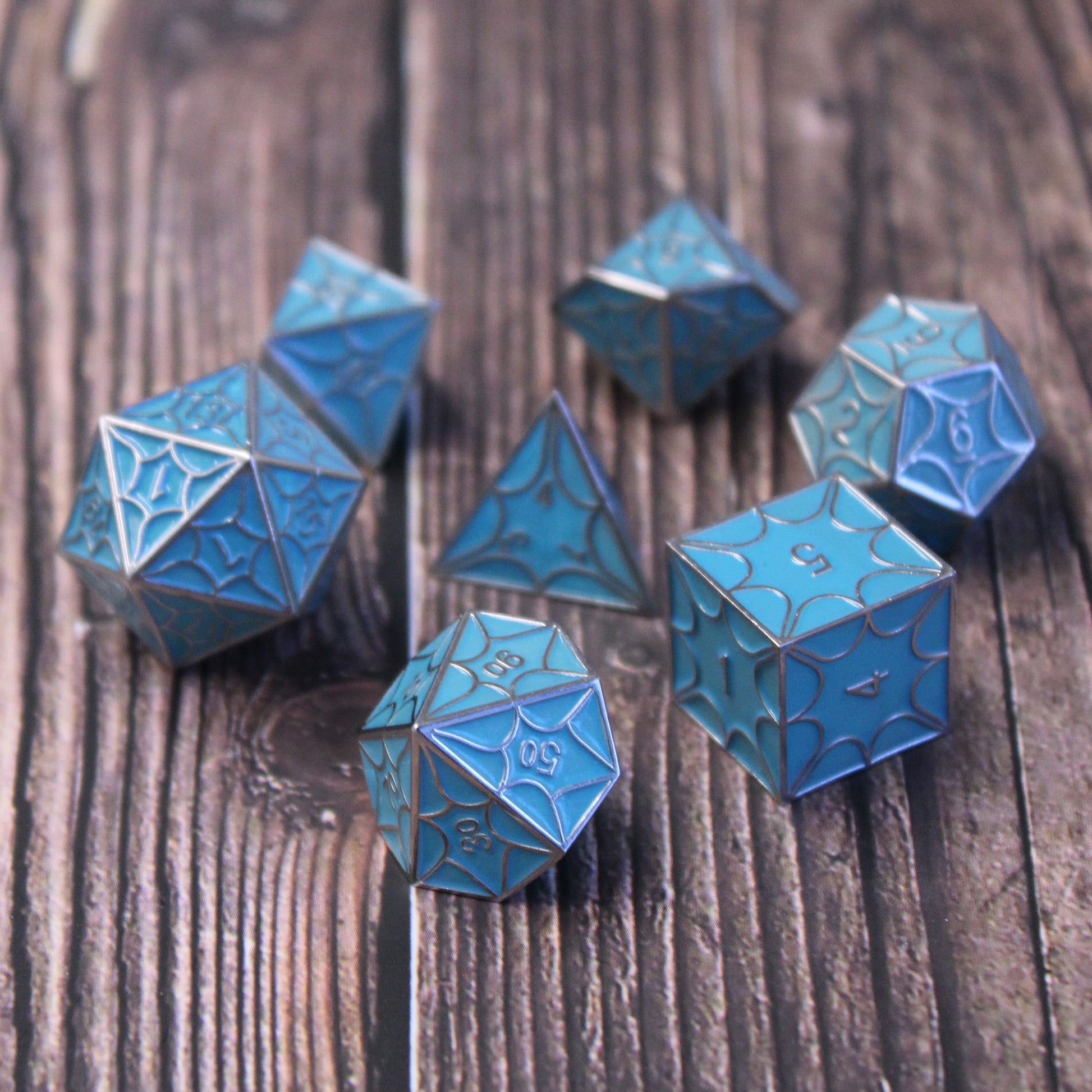 Close-up of faerie dragon dice set on wooden table, highlighting intricate dragon scale pattern for DnD.