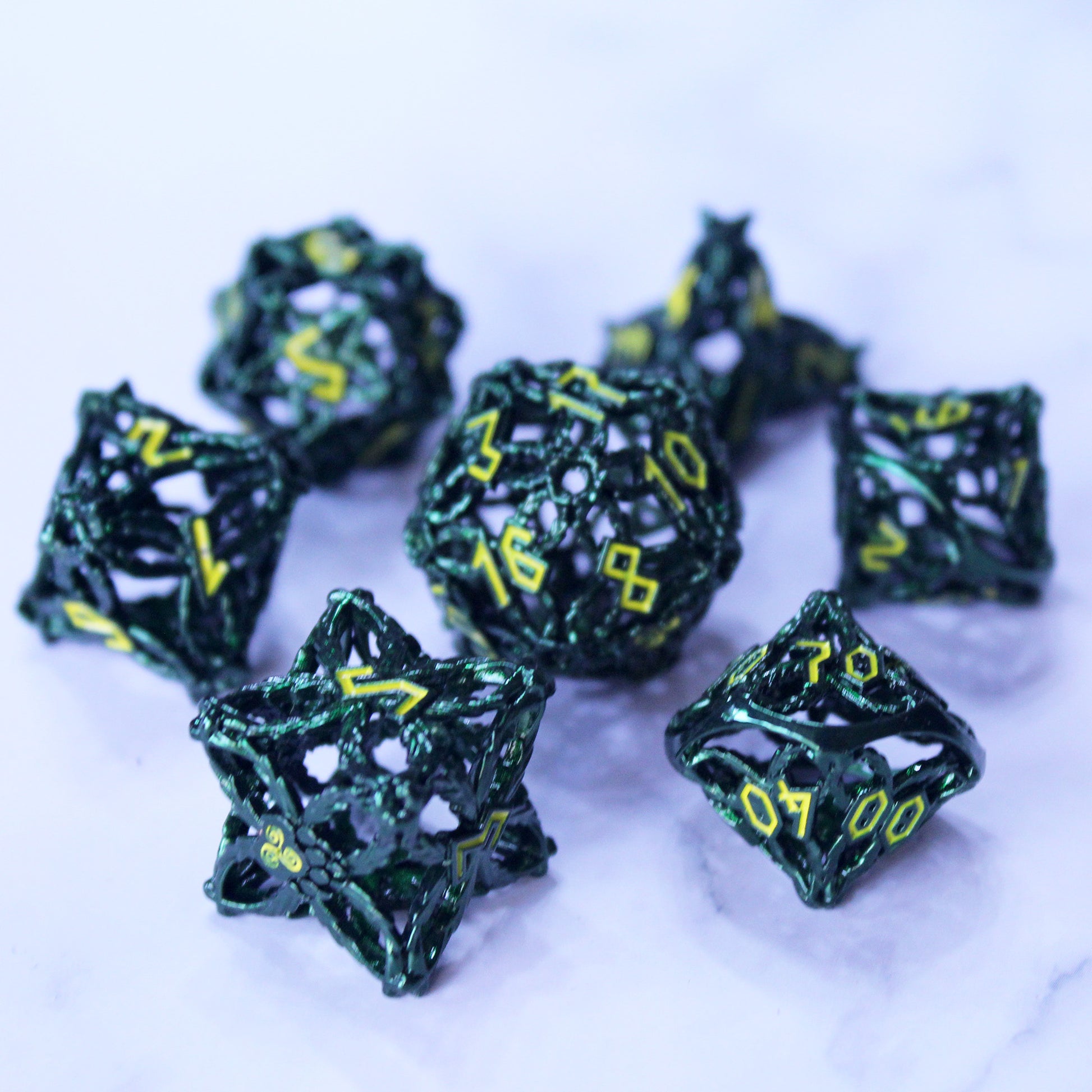 Set of hunter green druid-inspired hollow metal RPG dice with yellow numbers and a glyph-covered paw in place of the high number on a white background