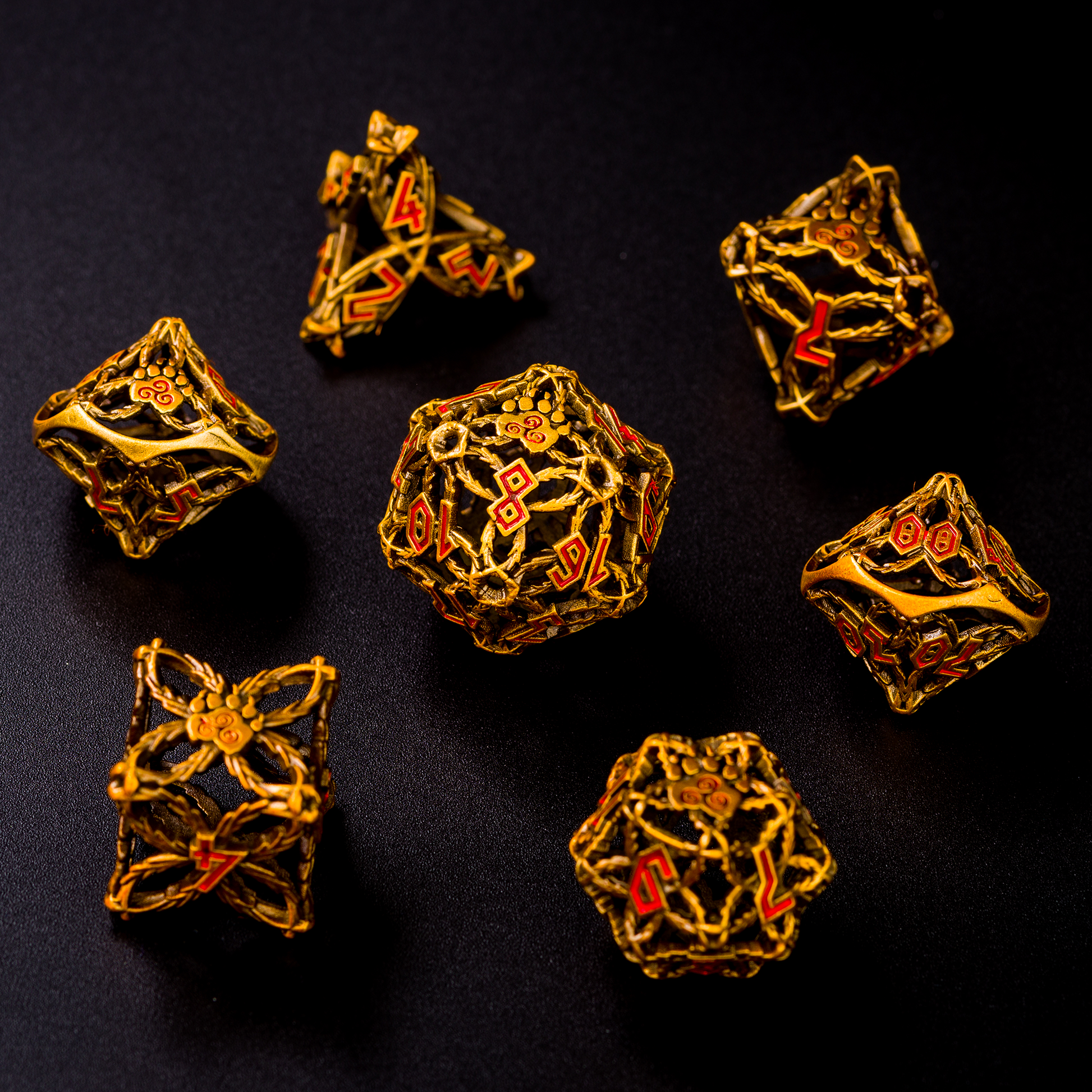 set of gold-colored druid-inspired hollow metal RPG dice with red numbers and a glyph-covered paw in place of the high number on a black background