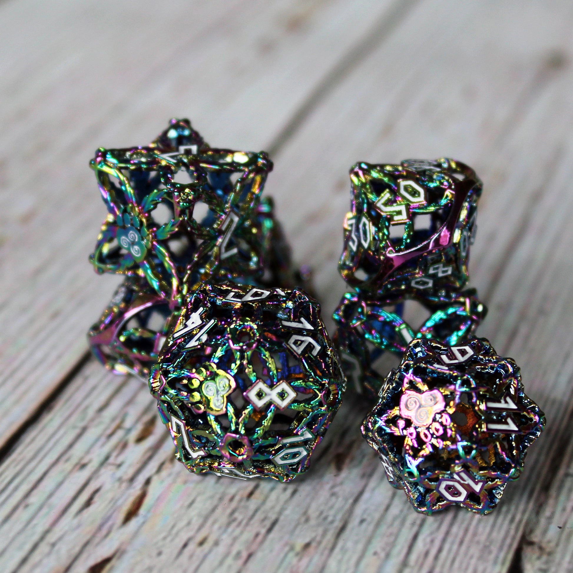 set of multicolored druid-inspired hollow metal RPG dice with white numbers and a glyph-covered paw in place of the high number on a wooden background