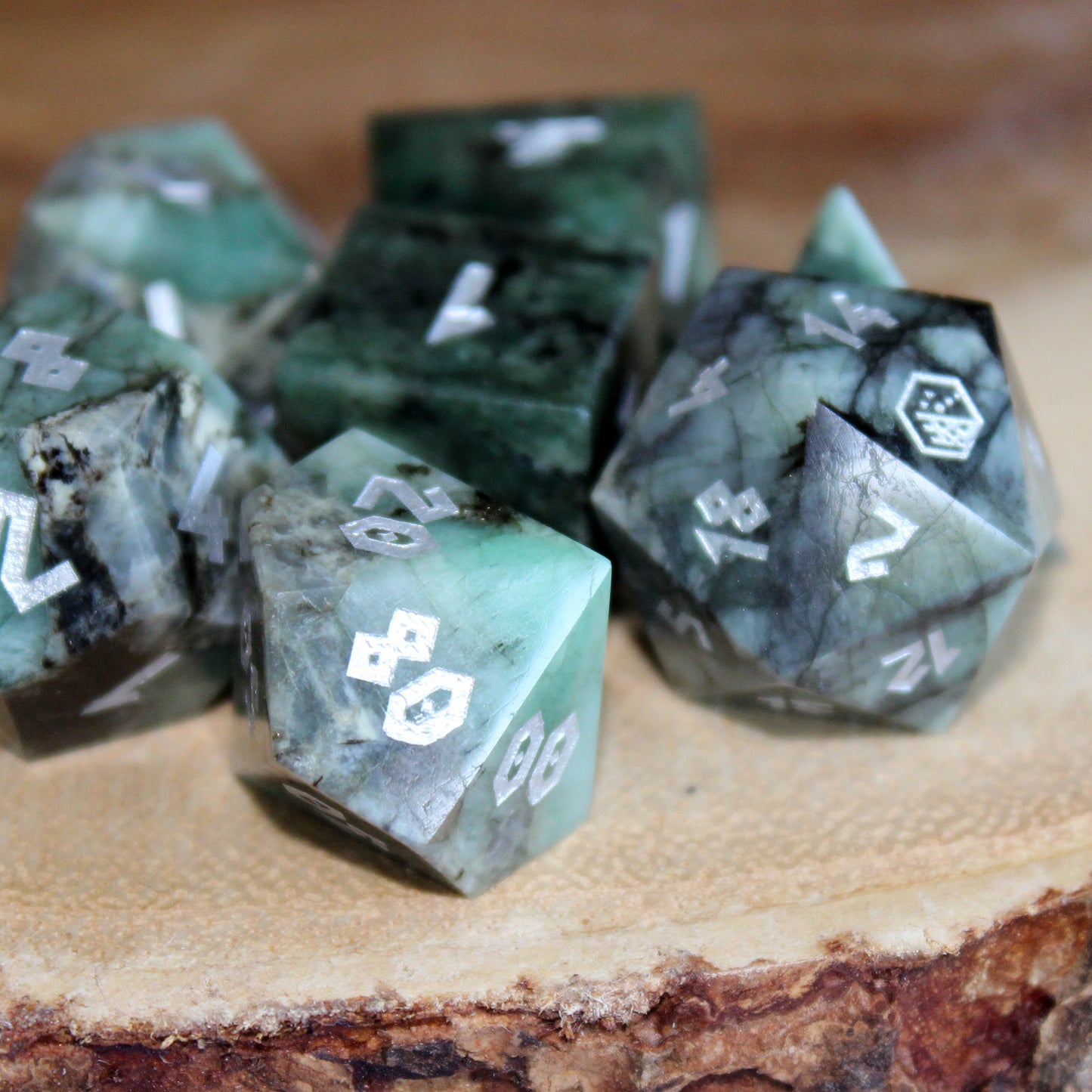 Emerald dice rpg set displayed on a table, showcasing the luxurious deep green gemstones and elegant silver inking.