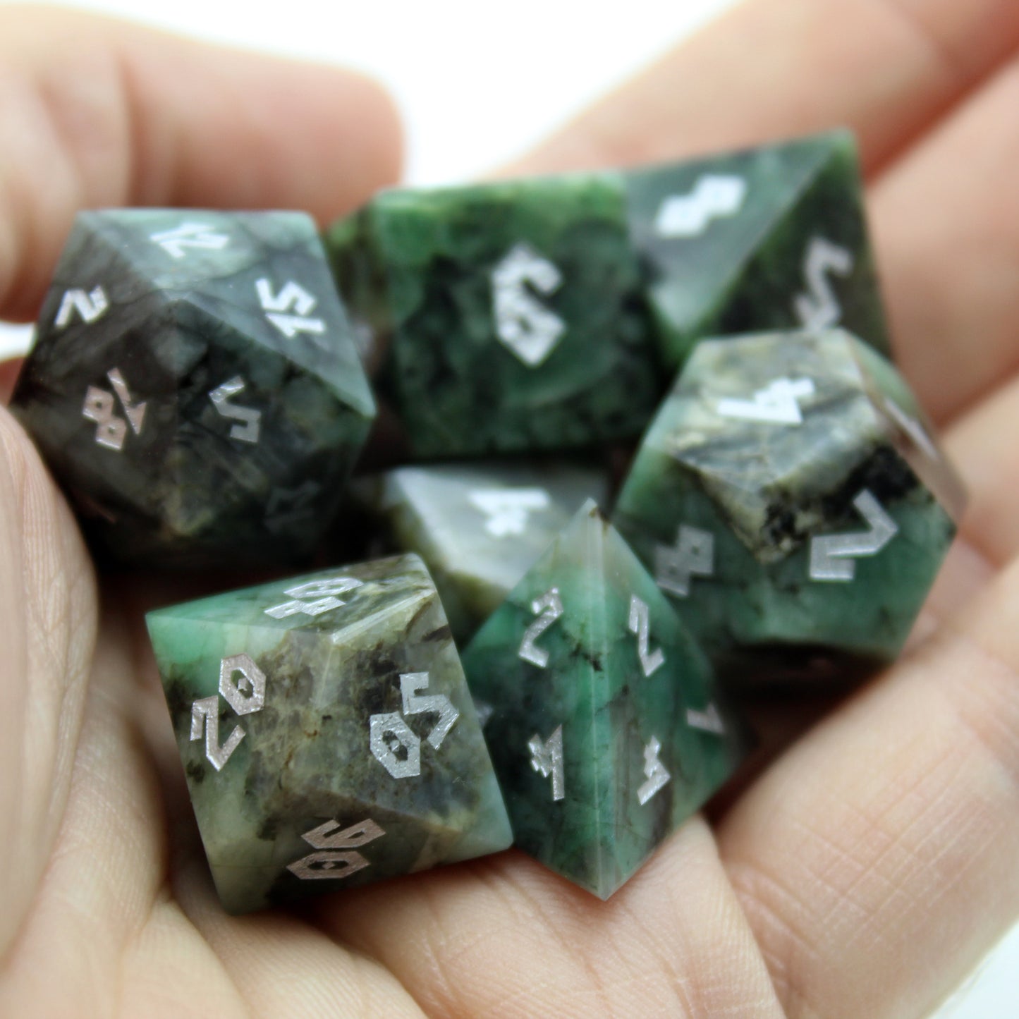 Emerald dice set held in hand for scale, highlighting the deep green color and 16mm size, ideal for any TTRPG enthusiast.
