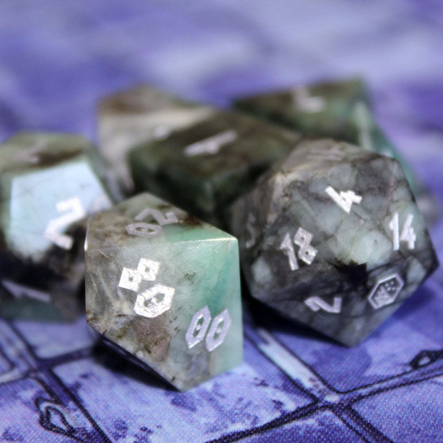 Close-up of the Emerald dice set on a battlemap, highlighting the polished green gemstones and clear Roman-inspired numbers, ready for Dungeons & Dragons adventures.