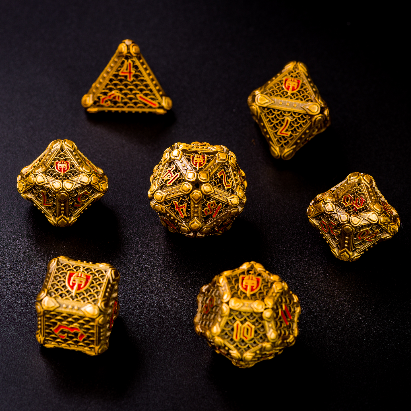 Set of gold-colored fighter-inspired hollow metal RPG dice with a chain mail background on each die face, red numbers, and a helmet, sword, and shield replacing the high number on each die on a black background