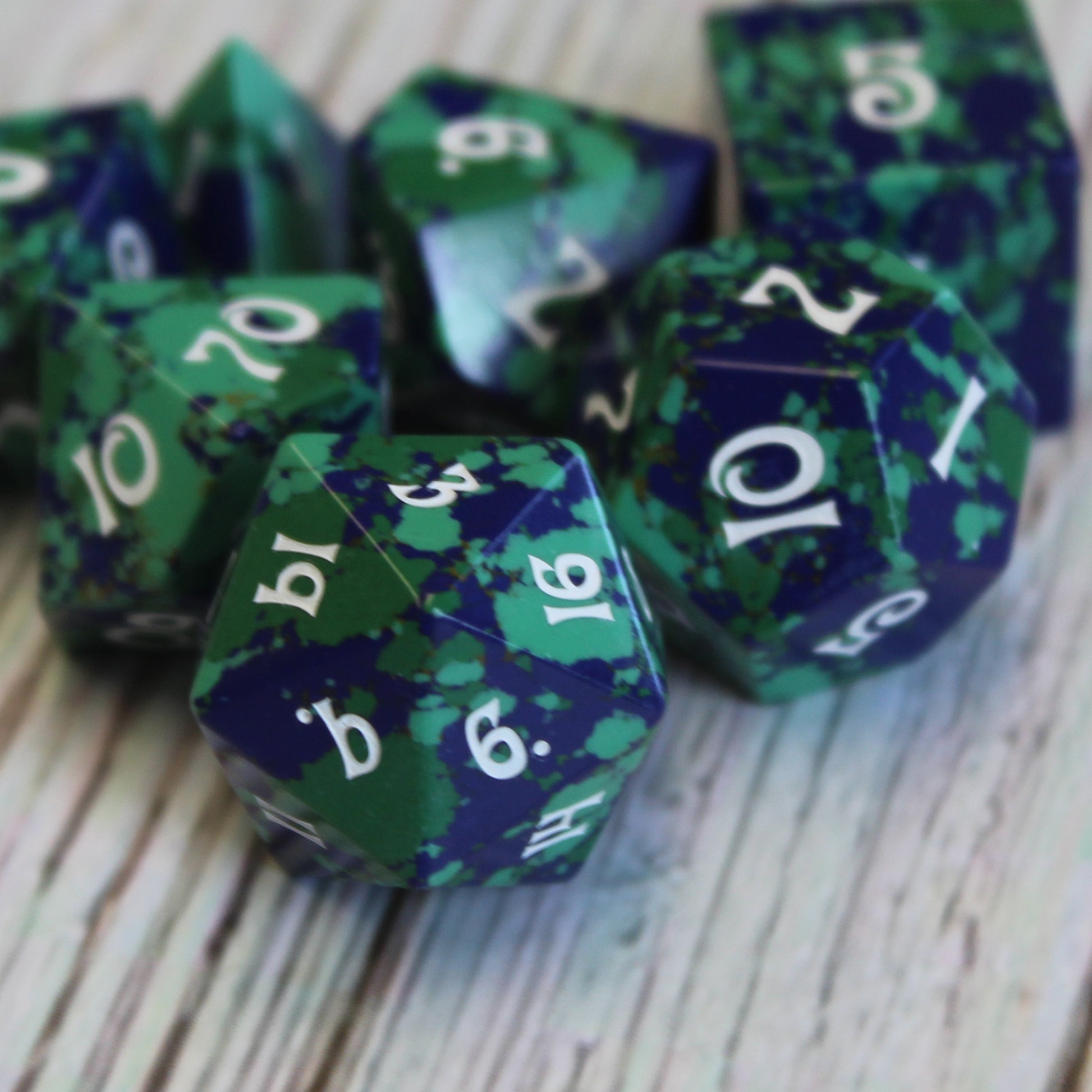 Dice set on white table, showcasing crushed turquoise and stone with deep colors for RPG players.