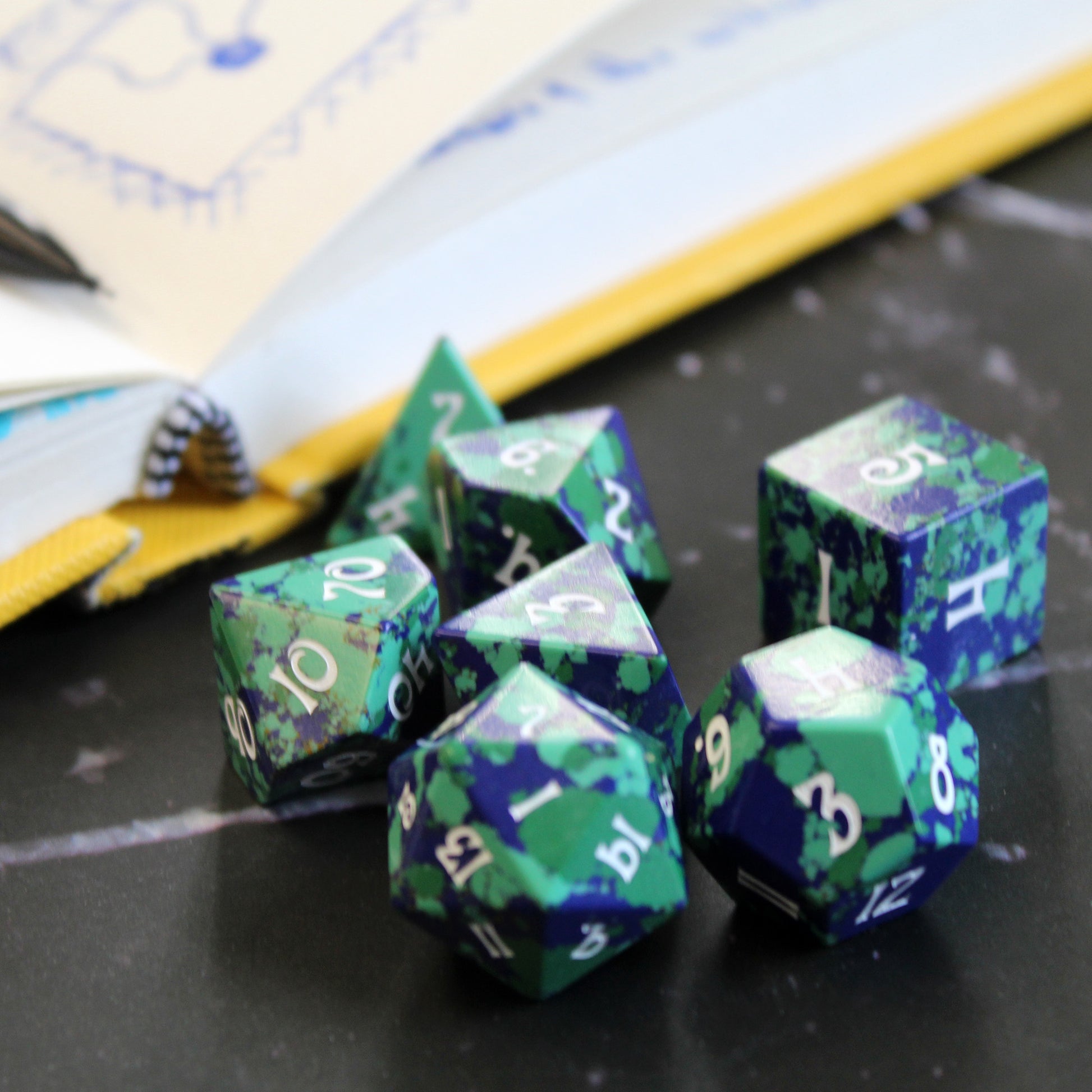 Gaia Dice Set in front of a game book, perfect for druids, rangers, and scouts in Dungeons and Dragons.