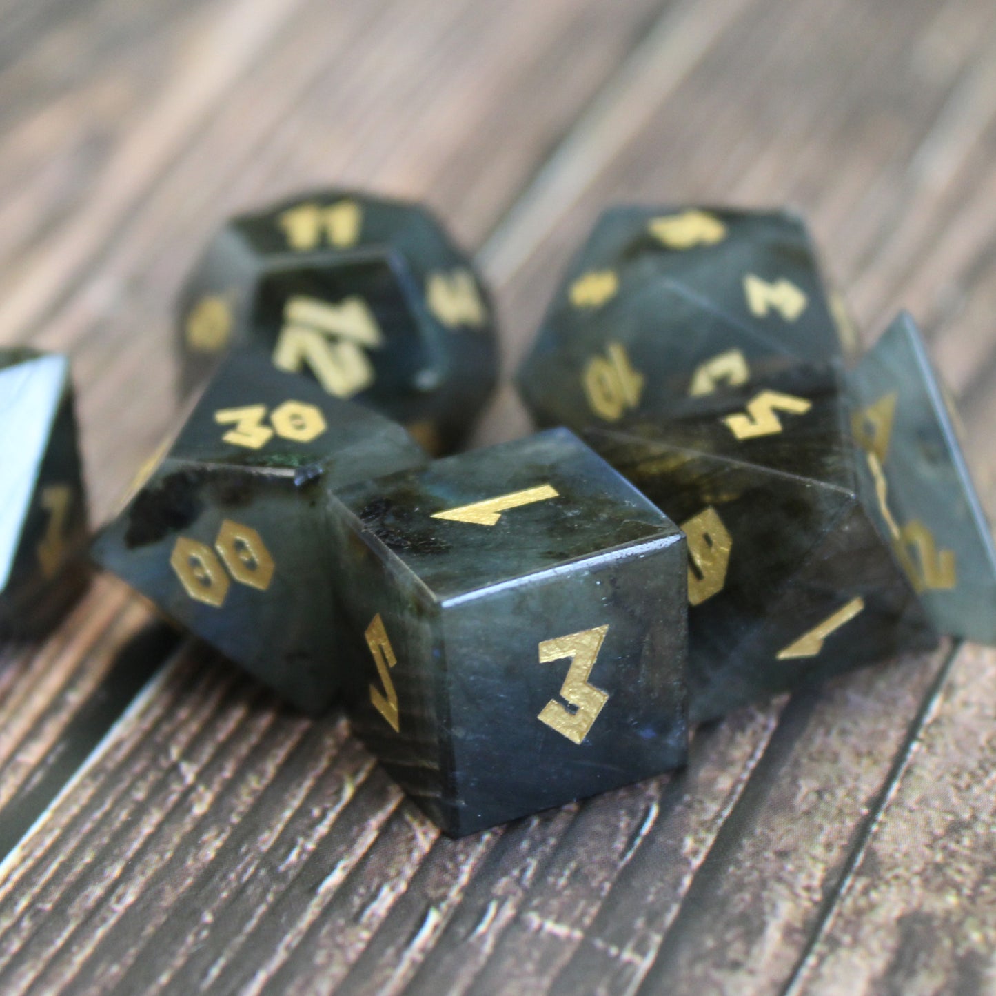 Labradorite dice set arranged in a pile on a wood surface.