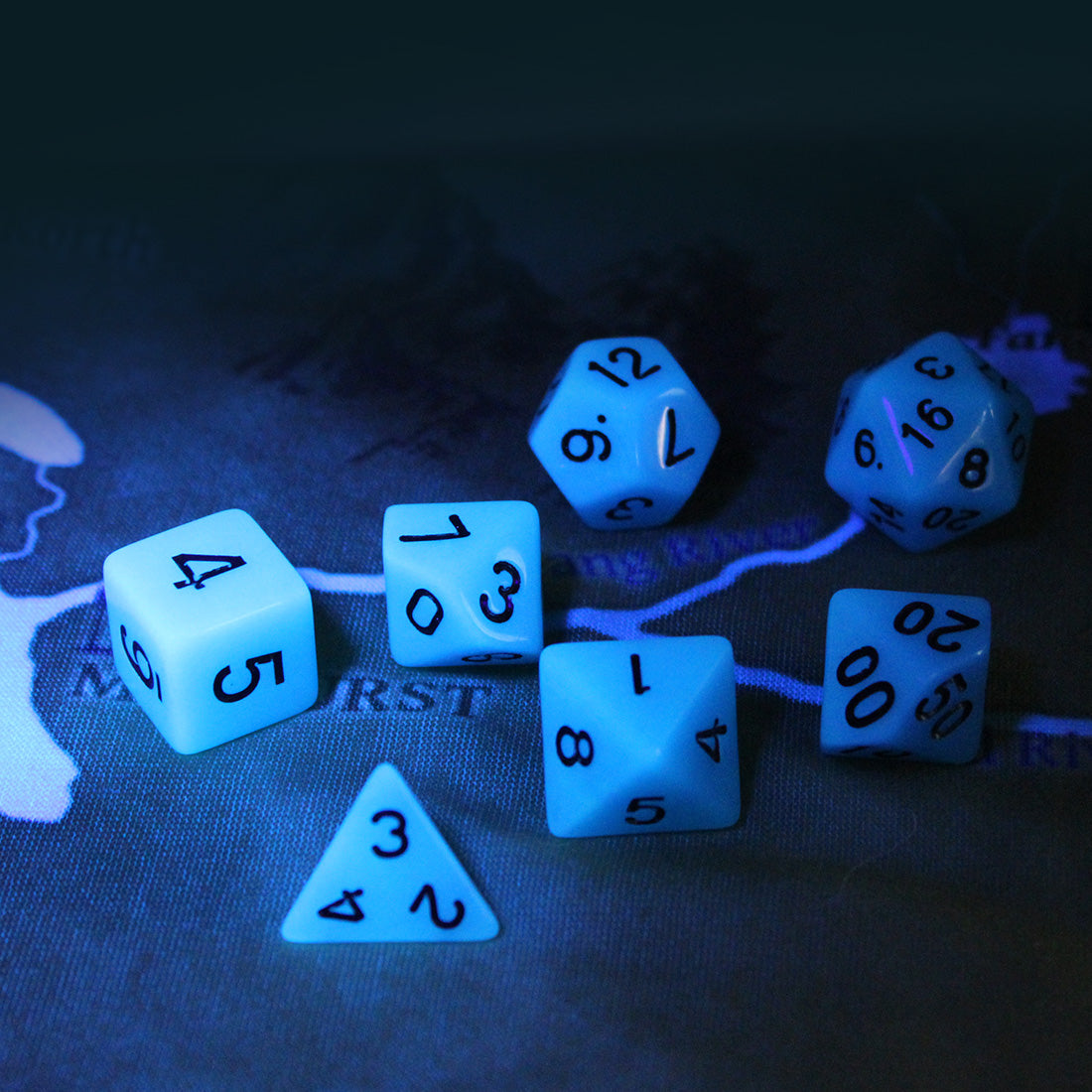 Glow in the Dark blue dice set in the dark on top of a play mat showcasing the glowing blue faces and dark numbering.