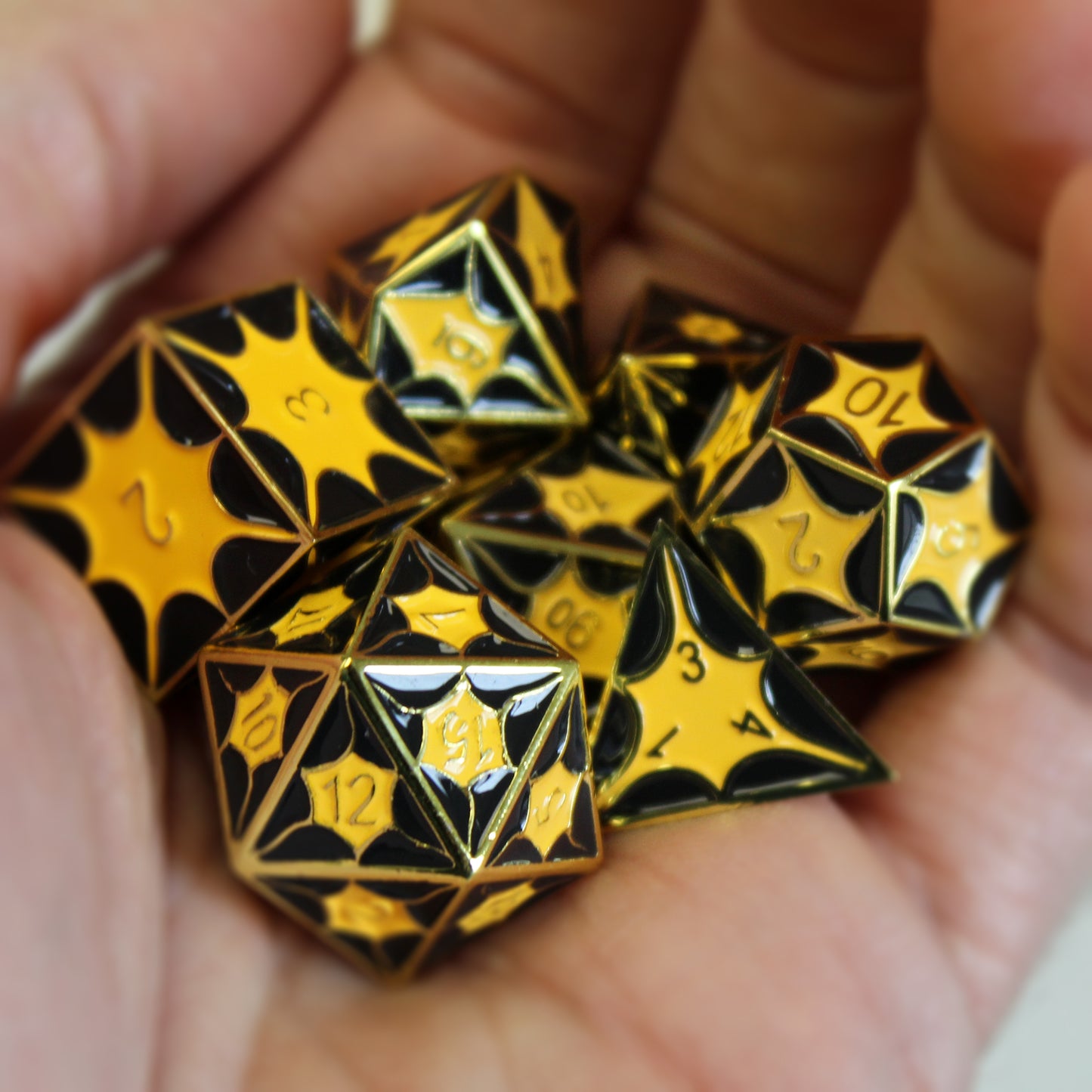 Dragonscale Dice in hand. Gold color metal scales with inset black and yellow enamel. Numbers are gold.
