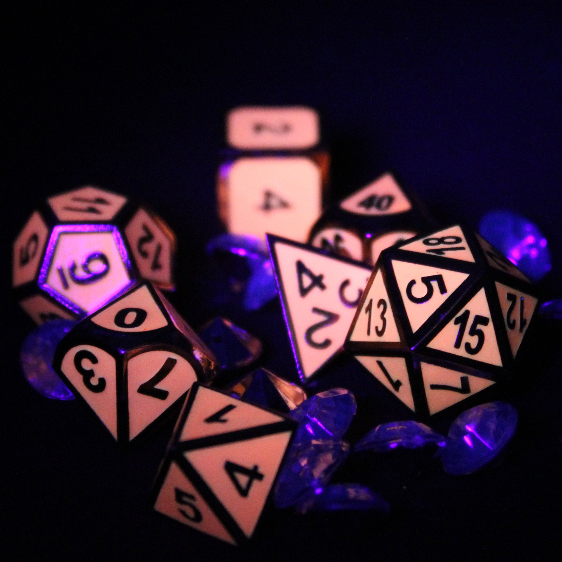 Imperial Glow in the Dark pink dice set on top of diamond-shaped gems, photographed in the dark to show off the light pink glow and dark numbering.