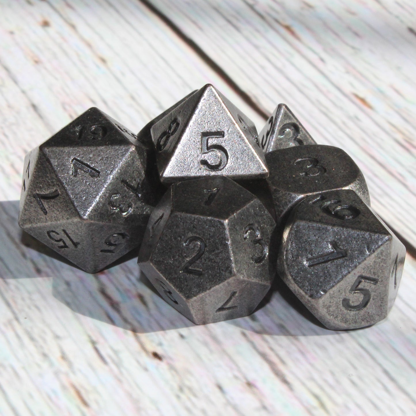 Primordial silver dice set arranged on light wooden surface