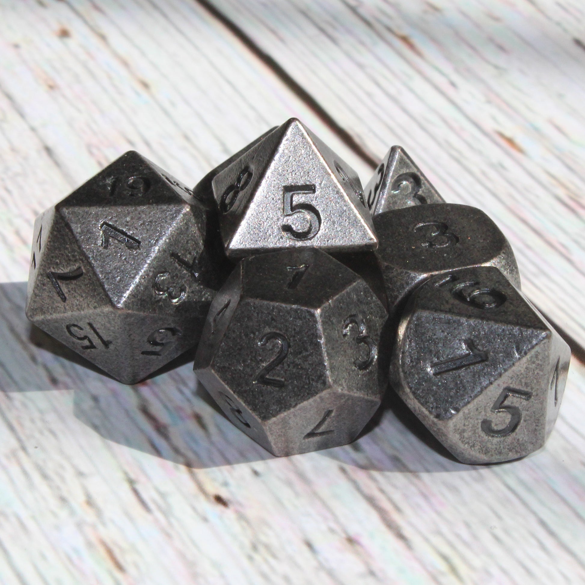 Primordial silver dice set arranged on light wooden surface
