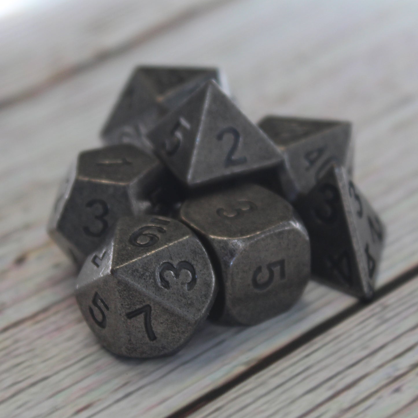 Primordial silver dice set arranged on a light wooden surface