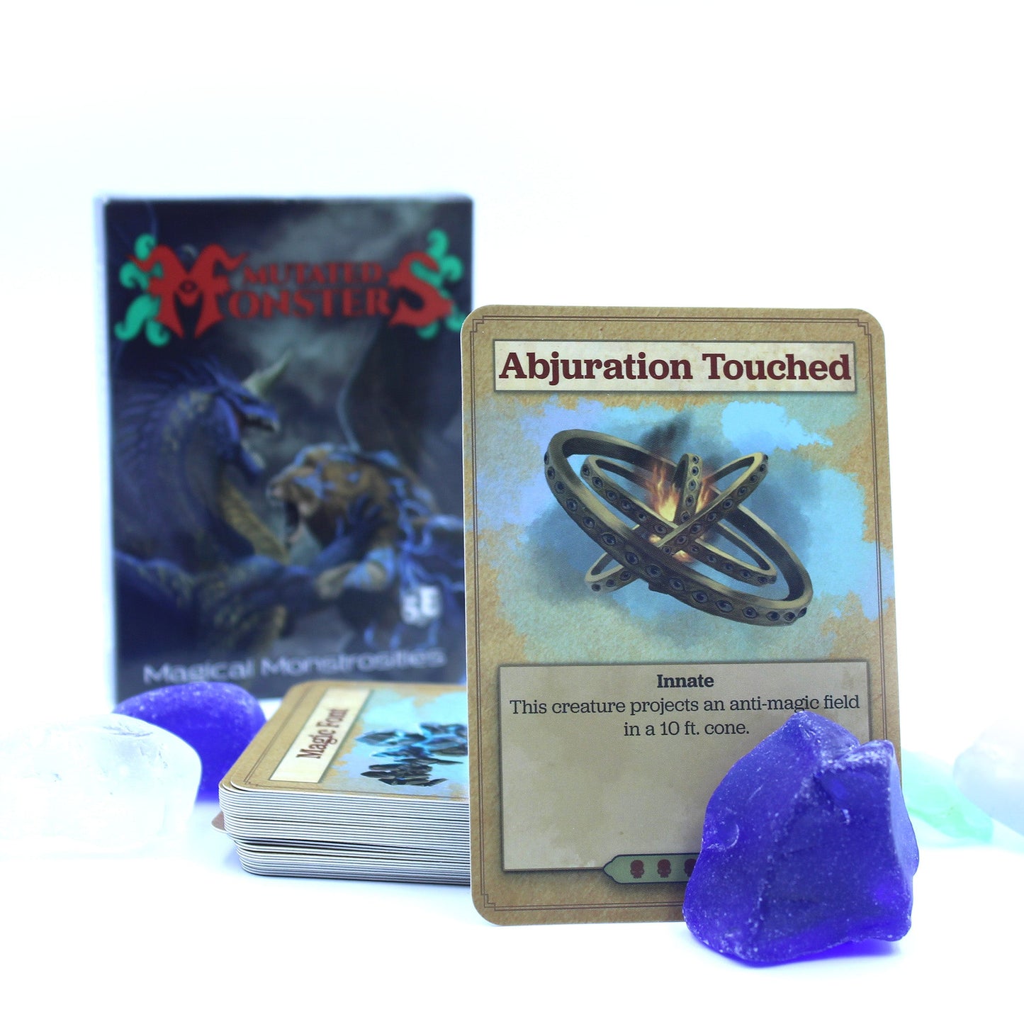 The deck box in the background with a stack of cards in the midground and a card propped up in the foreground. Cards are surrounded by a few blue and white stones. All on a white background.