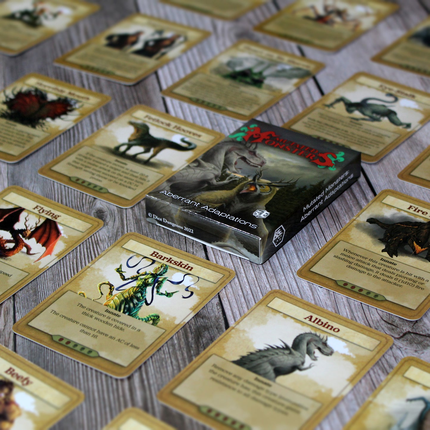 Deck box in the center of the image with individual cards from the deck spaced out equidistant from each other in a repeating pattern, all on a white wood paneled background.