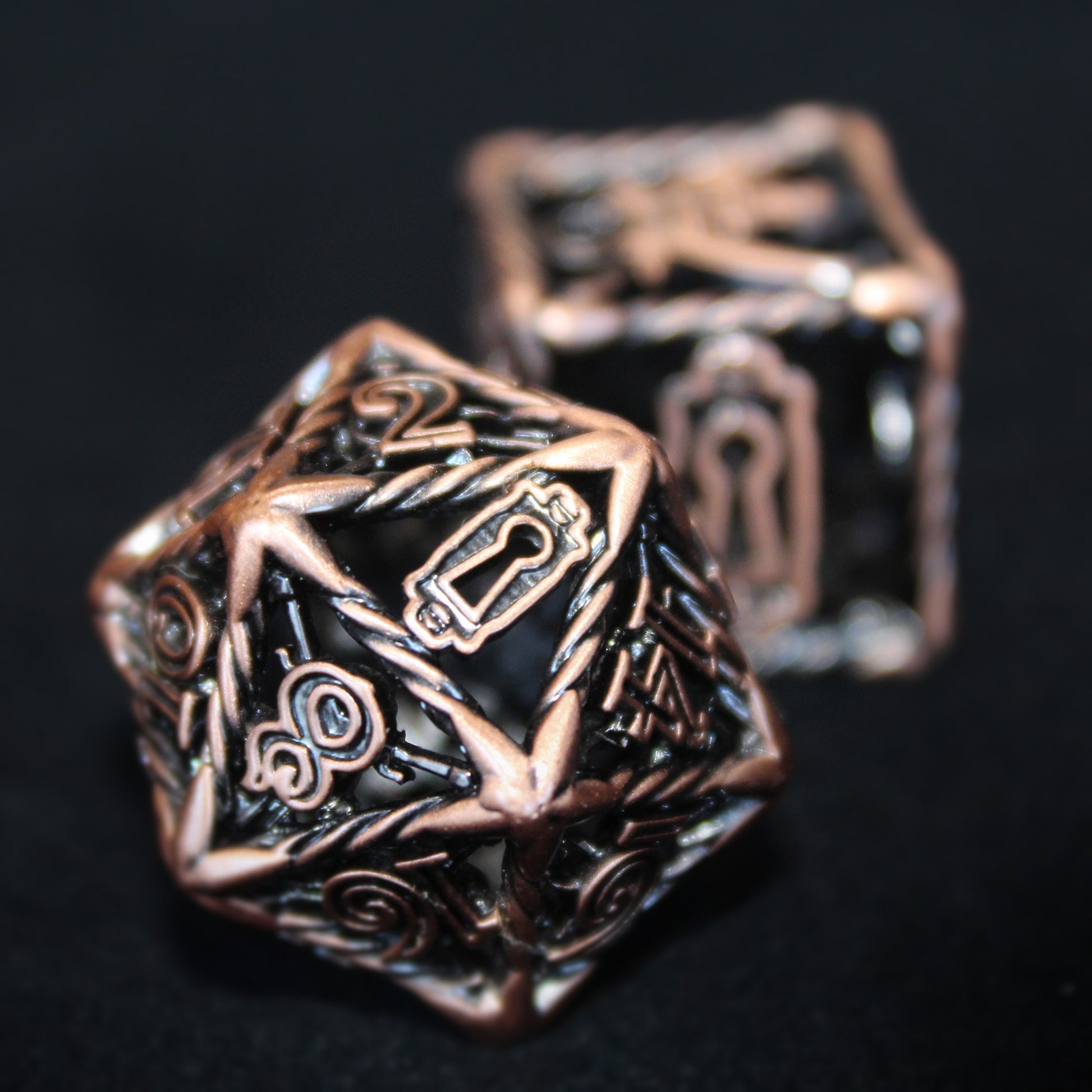 Copper Rogue D20 in foreground with a D6 out of focus behind. The dice are on a black surface, with the D20 is turned so that the 20 side is showing, which has been replaced with the image of a keyhole.