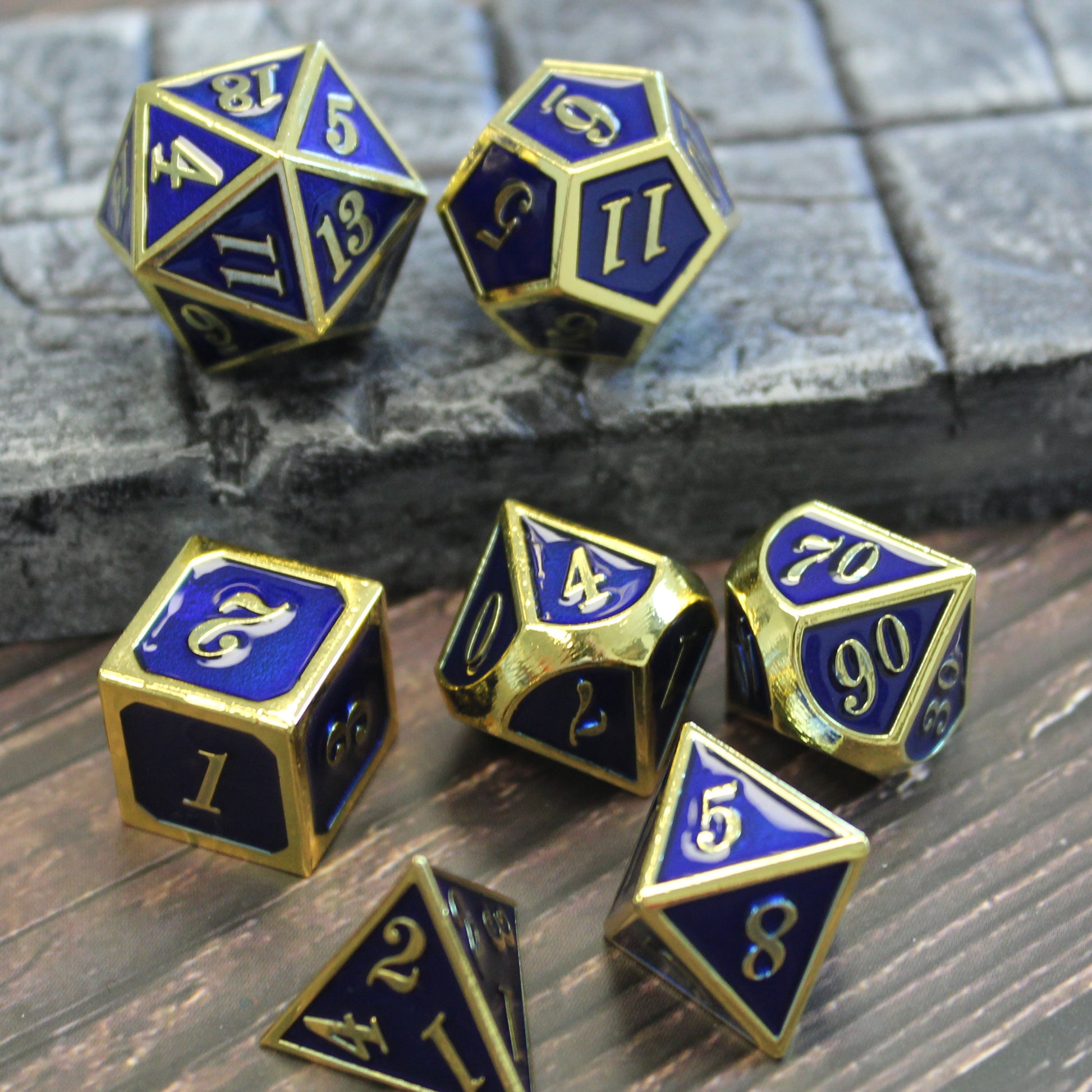 Imperial blue and gold dice set scattered partially on a wooden surface and partially a stone floor set piece