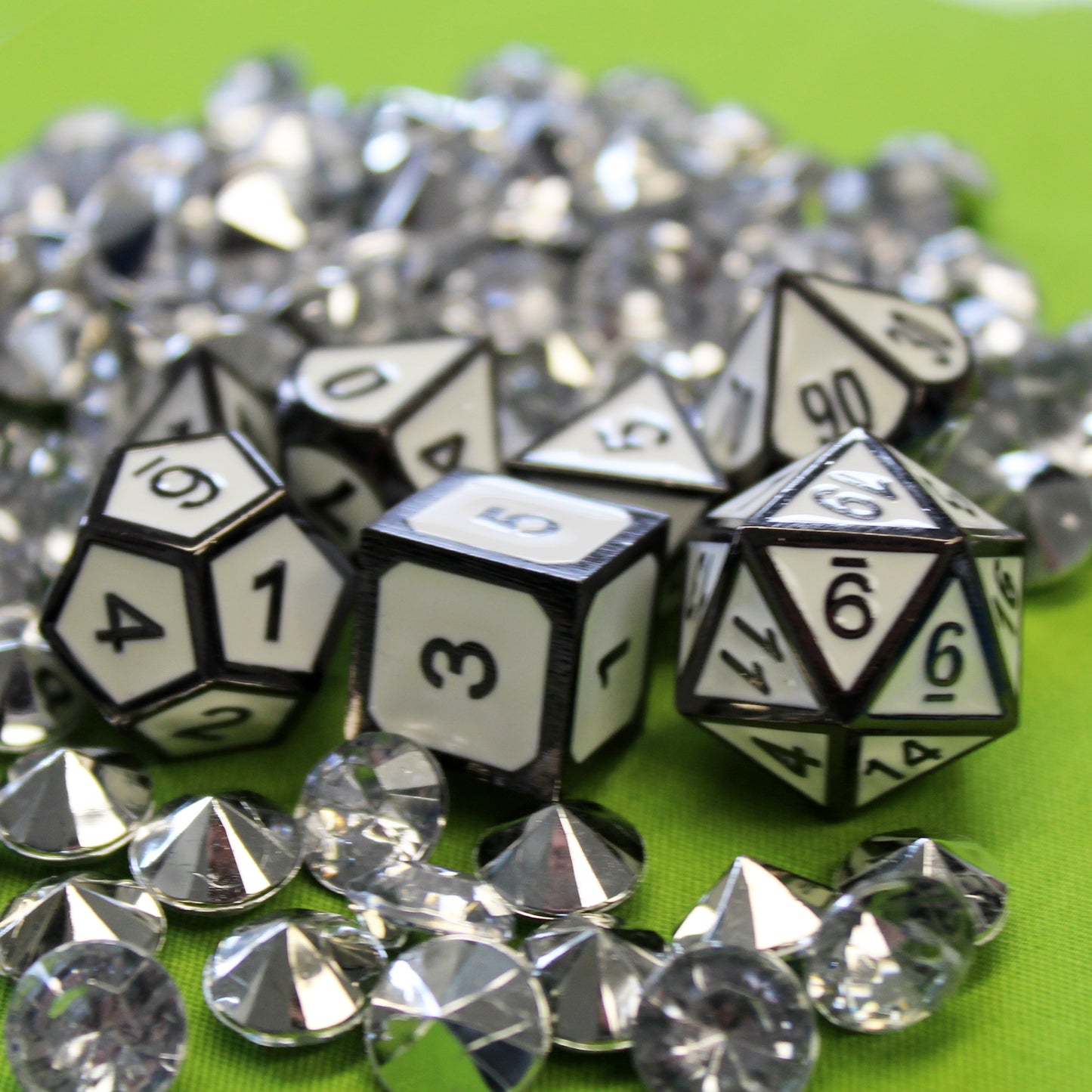 Imperial White dice set scattered on a lime green fabric, surrounded by small silver gems.