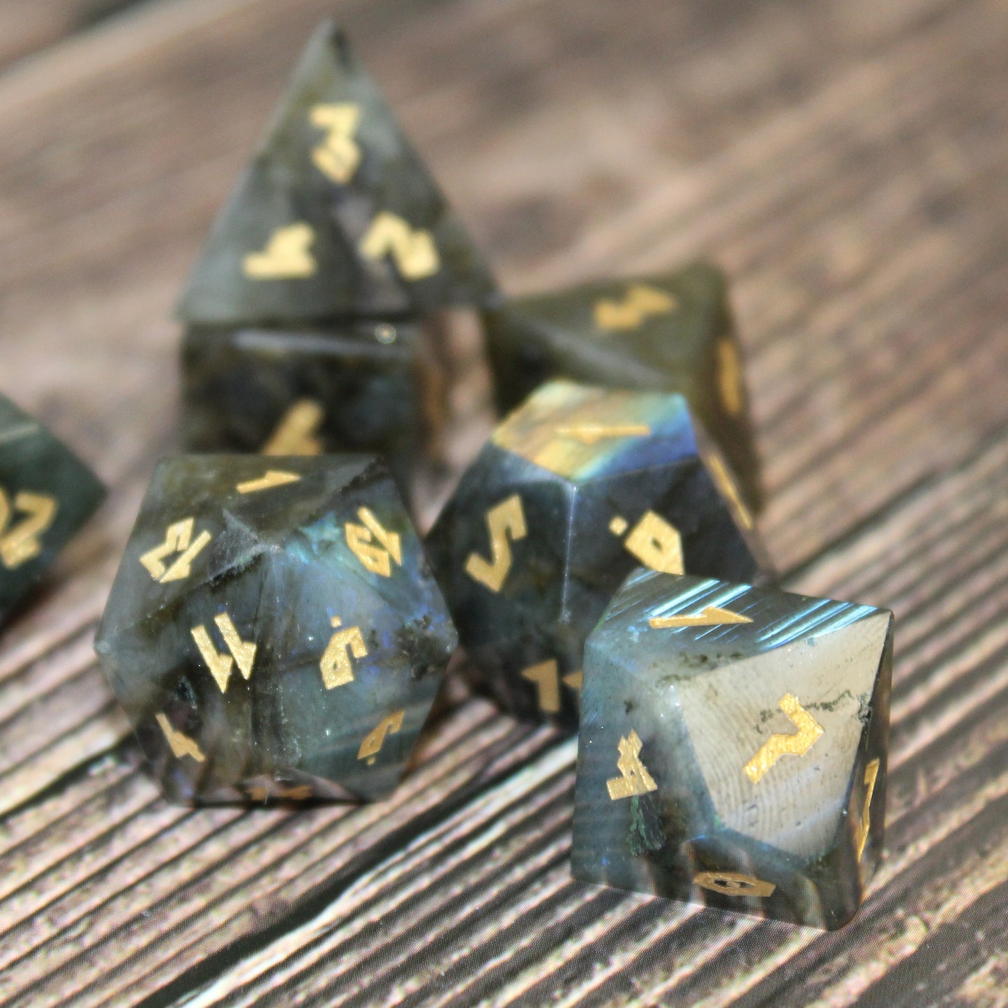 Labradorite dice set arranged in a pile on a wood surface.
