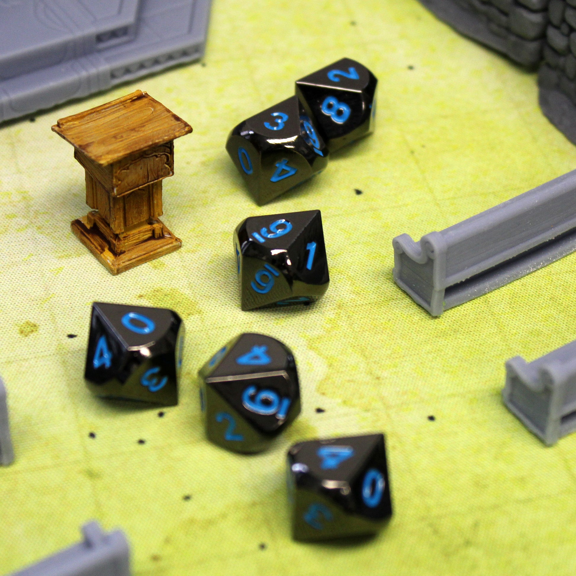 Metal Black Frost dice set scattered in a church set piece with pews and a pulpit on a green game mat