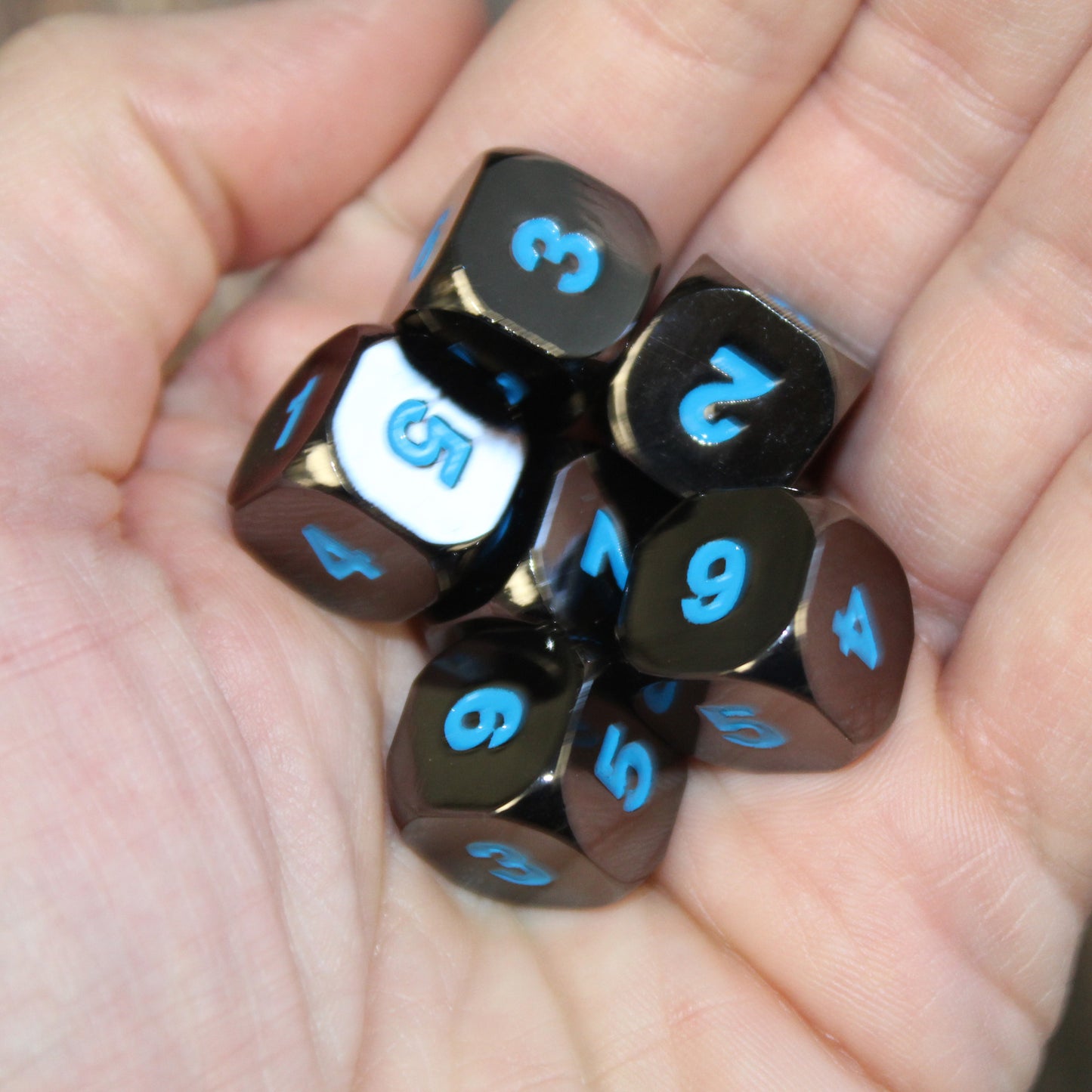 Six Black Frost D6 dice in the palm of a person's hand