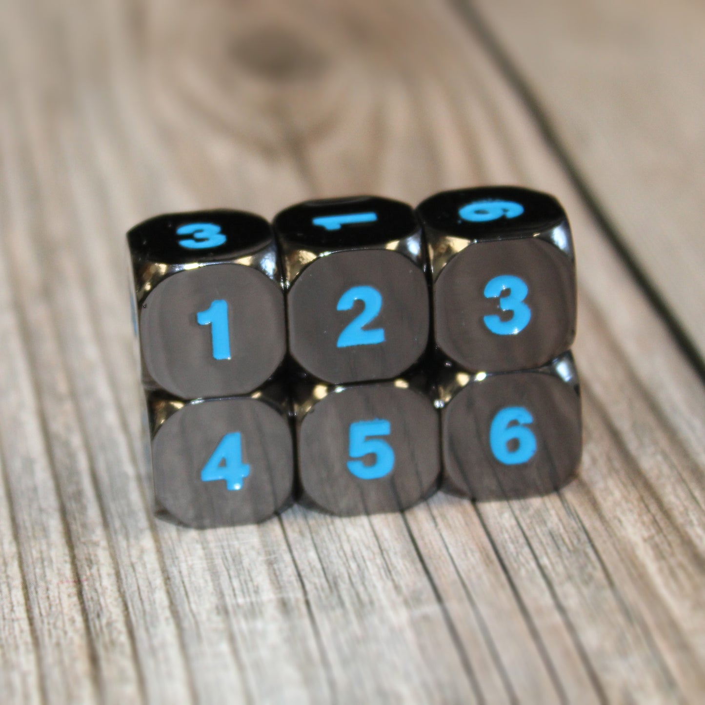 Six Black Frost D6 dice arranged in three stacks of two, each die showing a consecutive number from 1-6