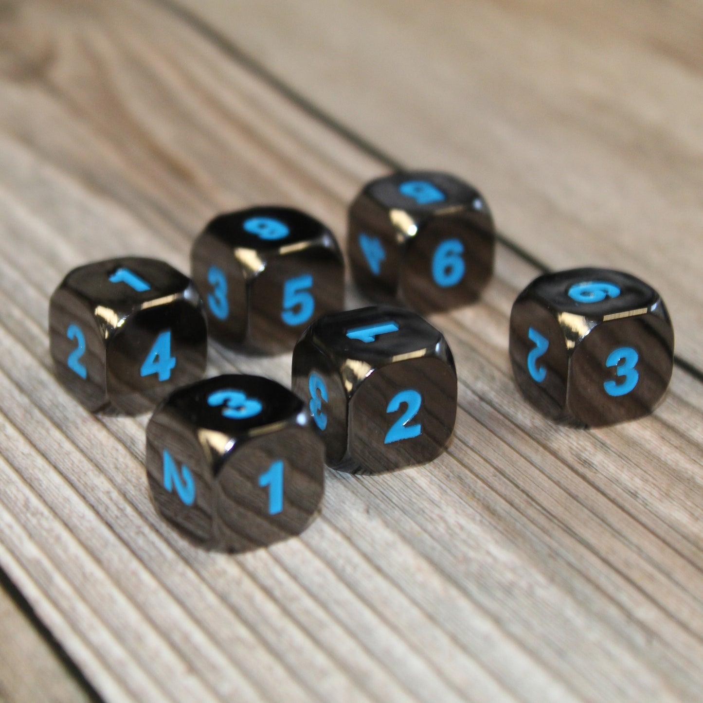 Six Black Frost dice scattered on a light wood surface