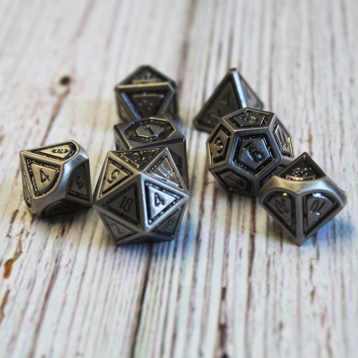 Metal Bullseye Dice set arranged in a scattered pile on a white wood surface.