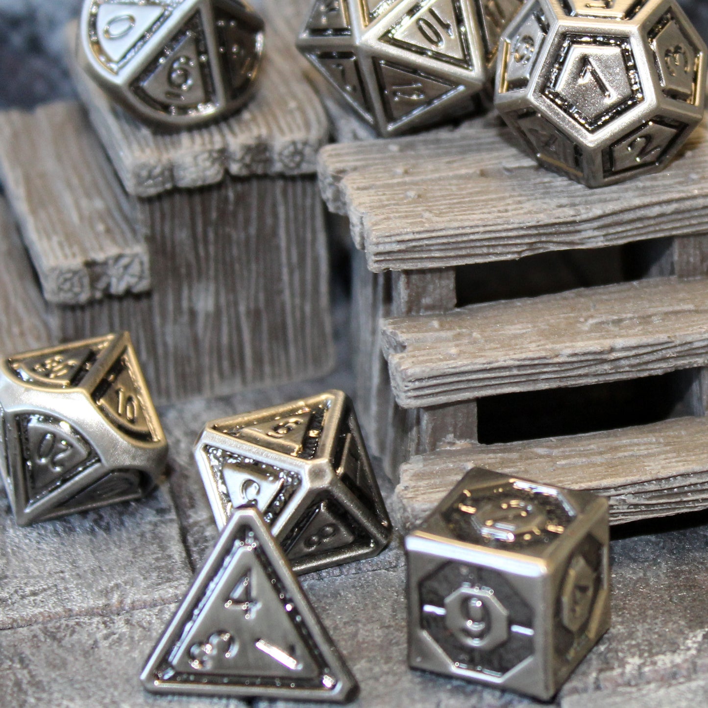 Metal Bullseye dice set arranged on top of and in front of a wooden step set piece on a gray stone floor.
