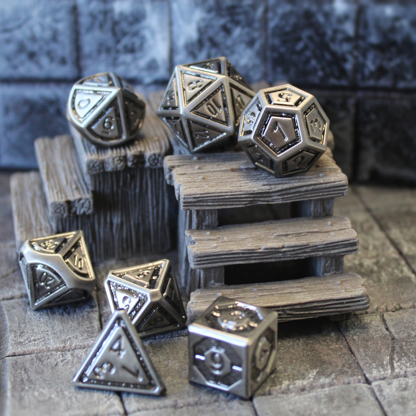 Metal Bullseye dice set arranged on top of and in front of a wooden step set piece. There is a gray stone floor and gray stone wall set pieces all around.