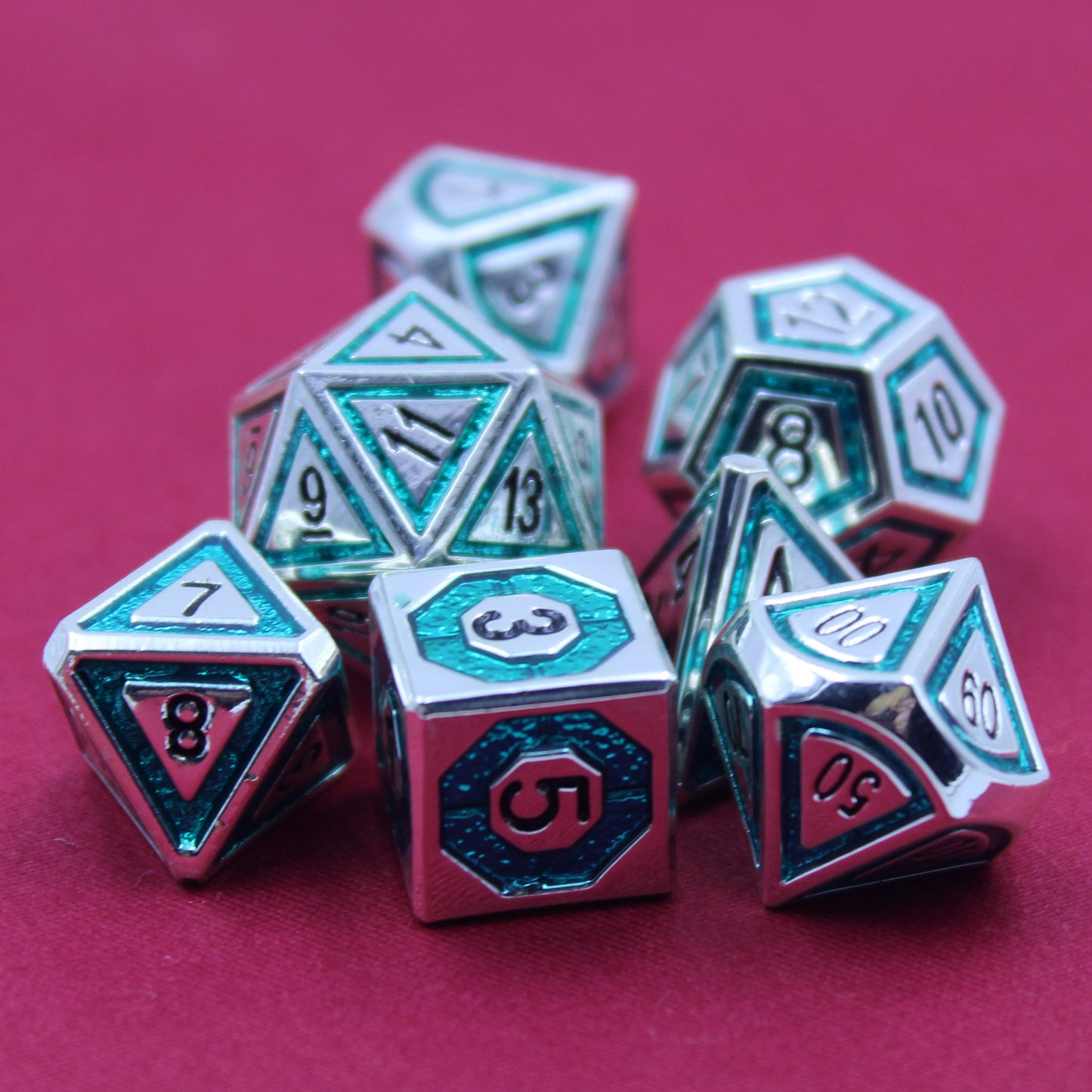 Closeup photo of silver dice with bullseye teal inlays on a red background.